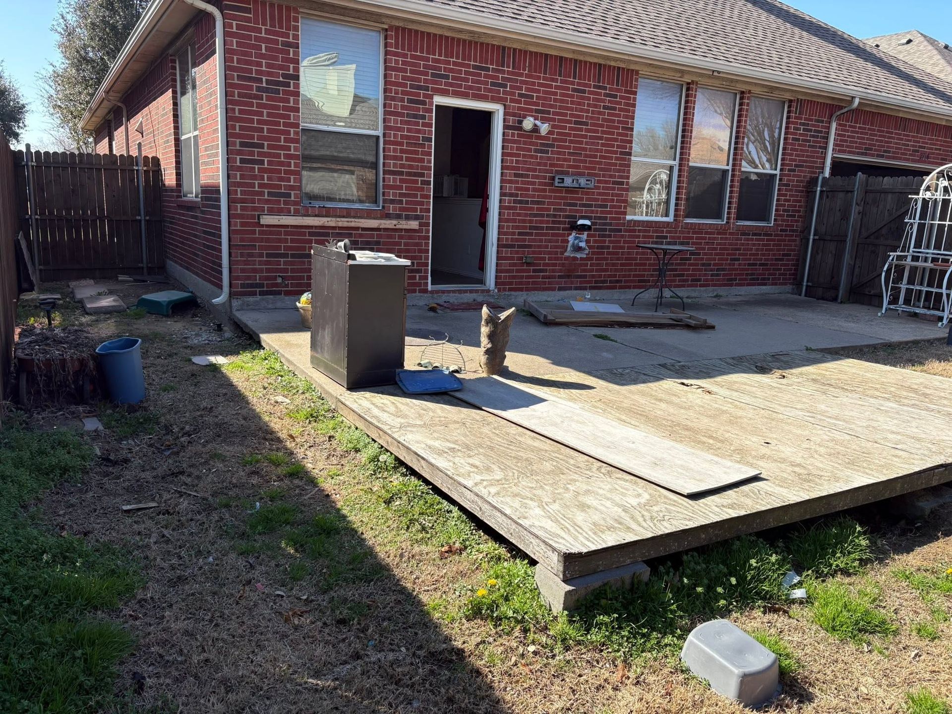 Backyard with a red brick house and a small raised wooden deck under construction