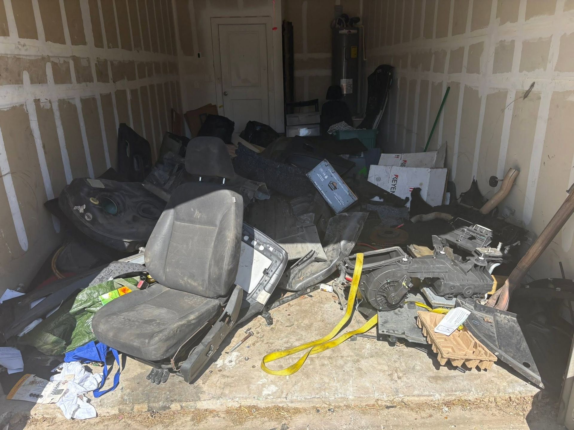 Damaged moving van interior filled with scattered black chairs, debris, and yellow straps