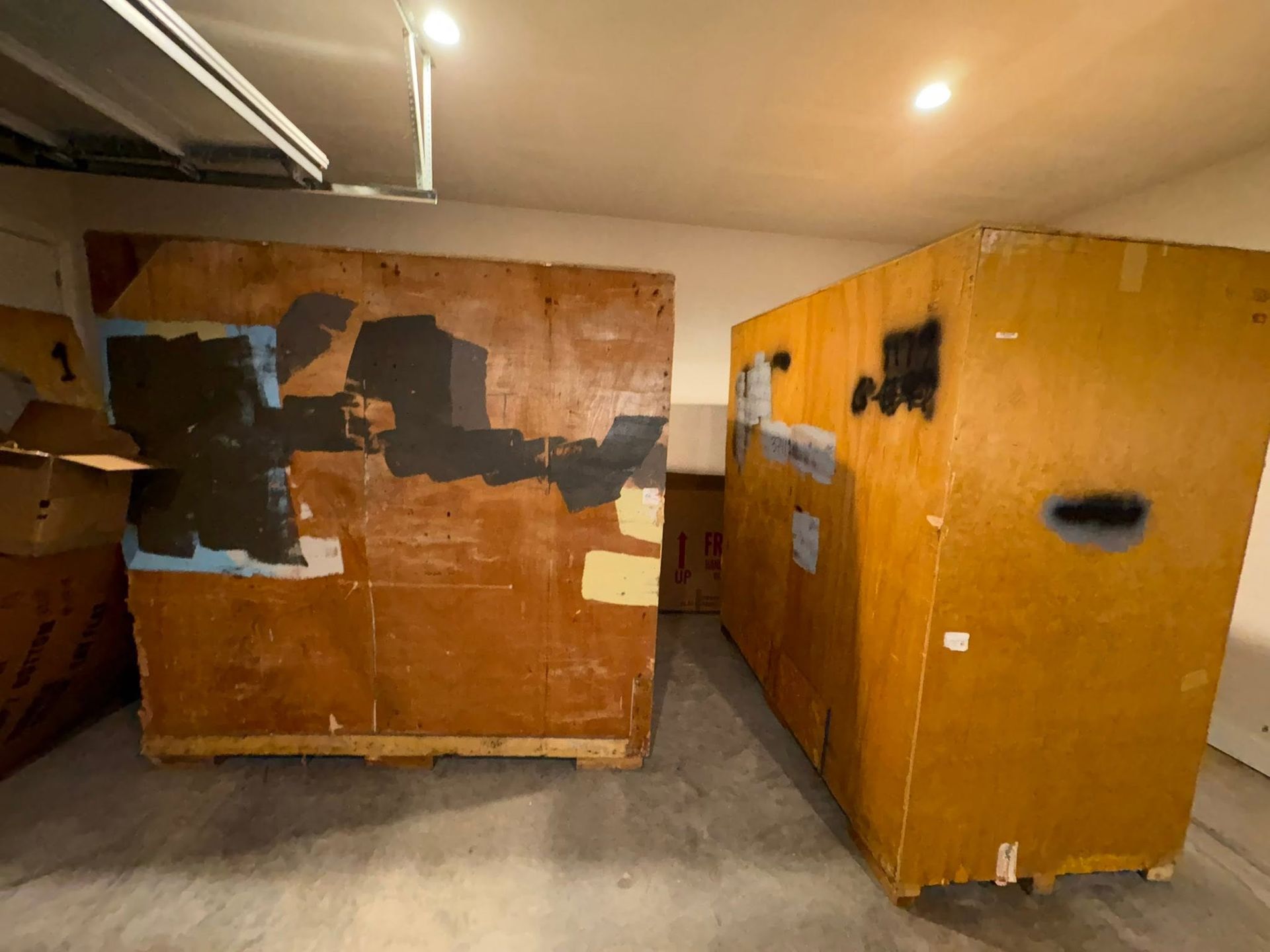Interior storage room with two large wooden crates, one patched with black and white markings.