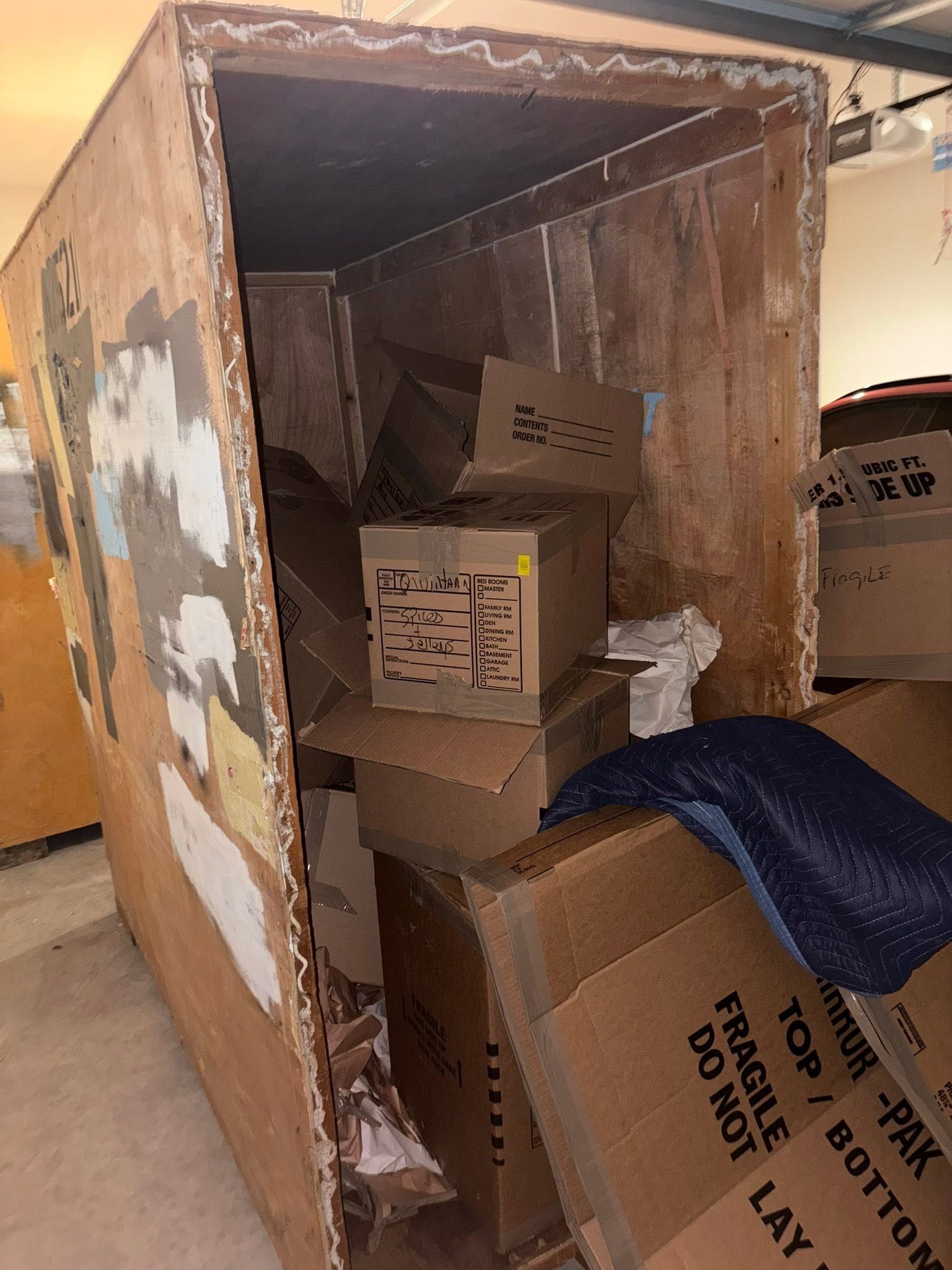 Cardboard dumpster or bin filled with stacked cardboard boxes and packing material, viewed from the open front.