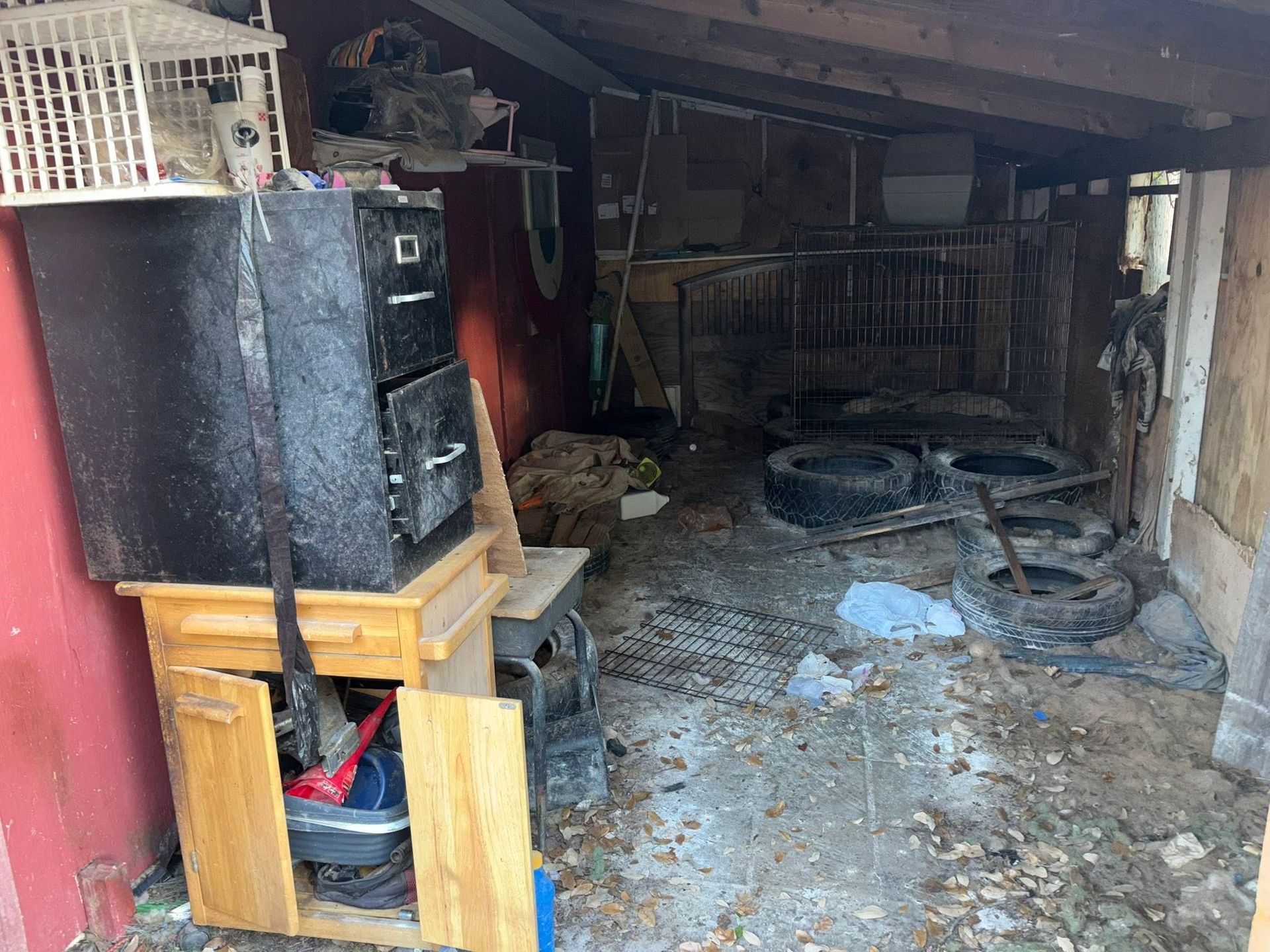 Messy basement with debris, stacked boxes, and damaged ceiling beams