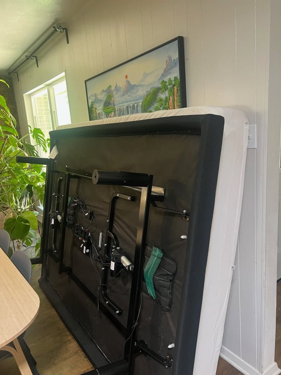 Wall-mounted fold-down TV or desk in a hallway, with a framed landscape painting above it.