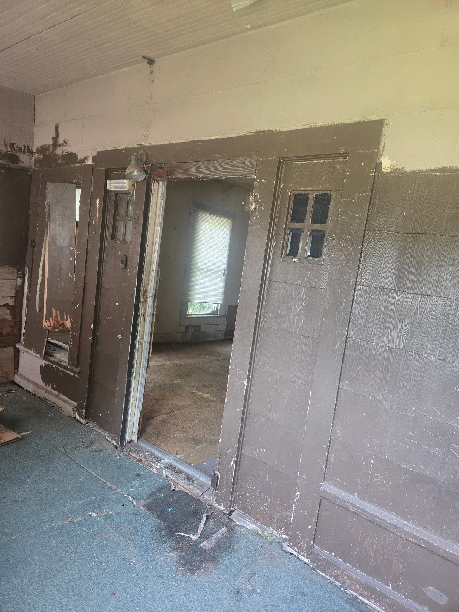 Damaged hallway with exposed wall patches, open doors, and debris on the floor