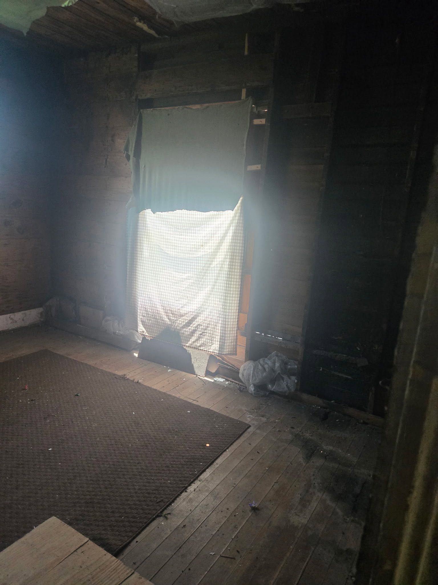 Dim interior room with a bright sunlit doorway covered by a partially closed curtain.