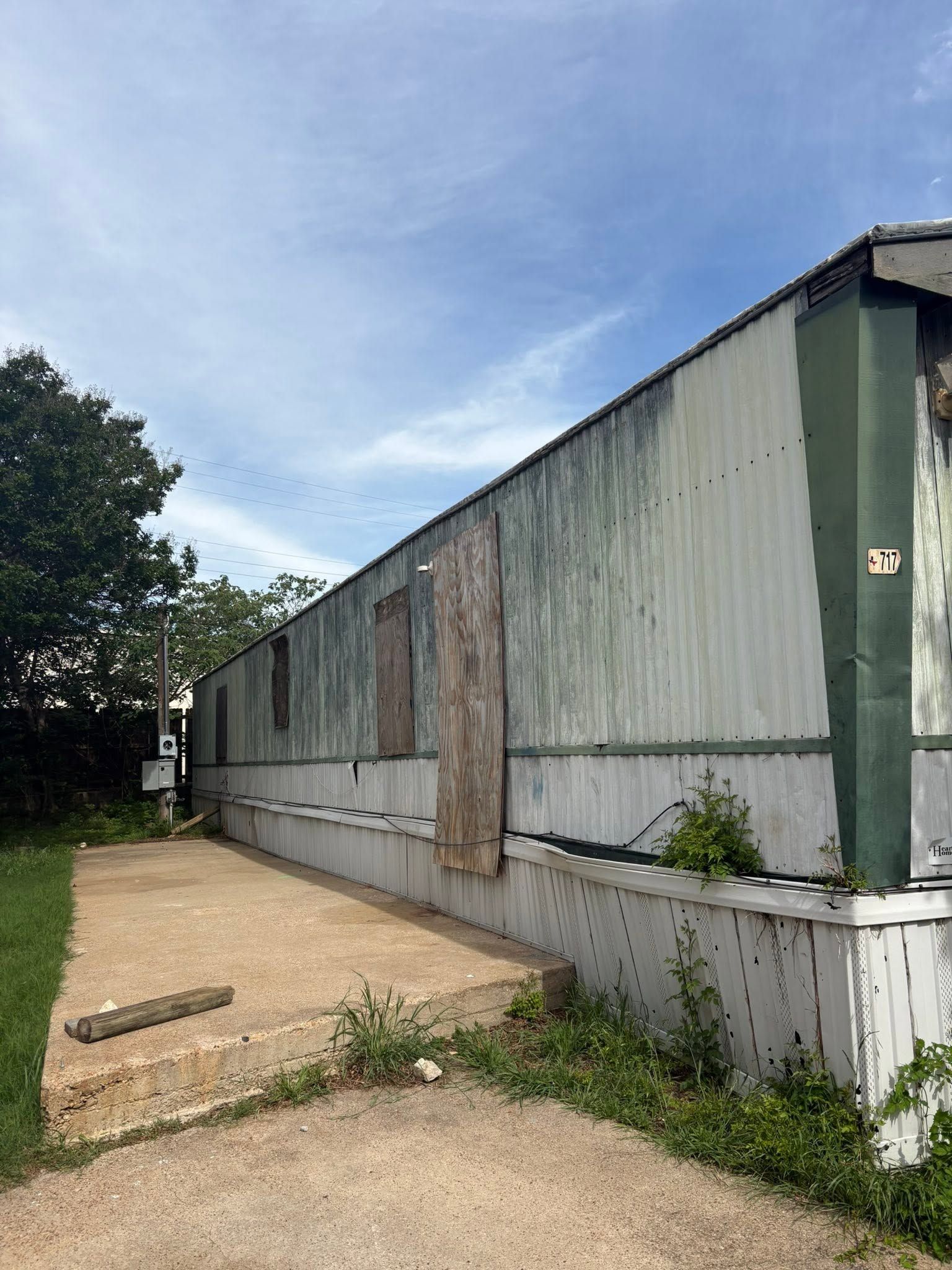 Long corrugated metal building beside a gravel path under a cloudy blue sky