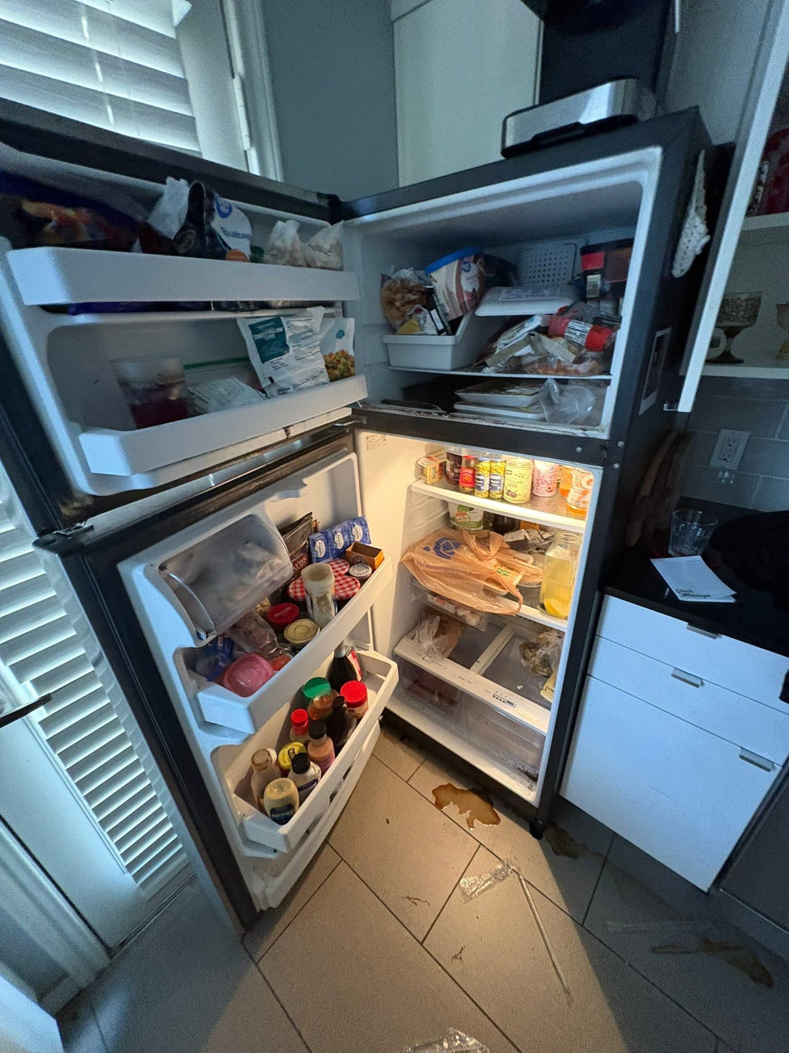Open refrigerator with shelves full of food and drinks in a kitchen doorway.
