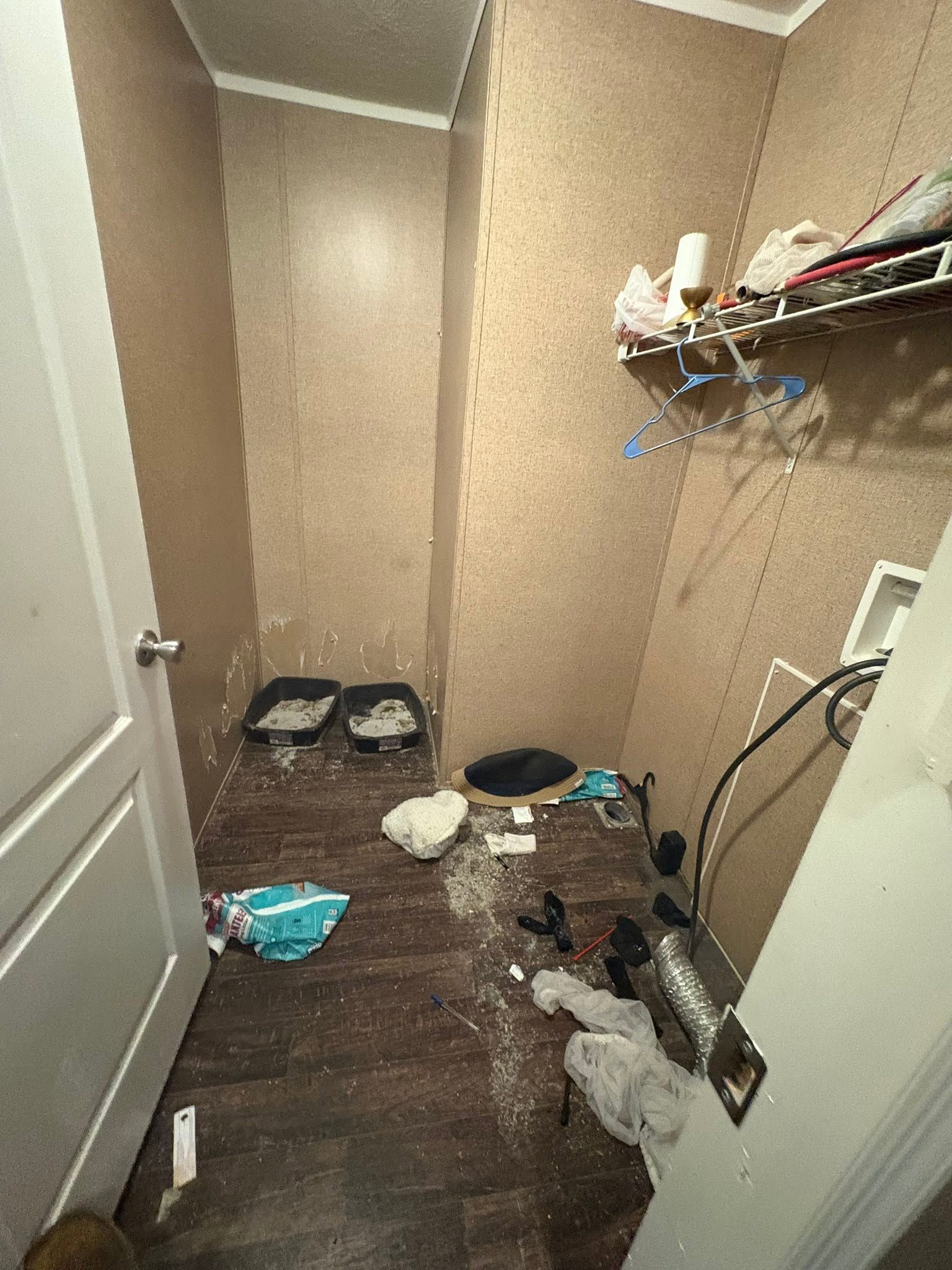 Narrow cluttered closet with scattered items, shelves on the right, and an open door on the left.
