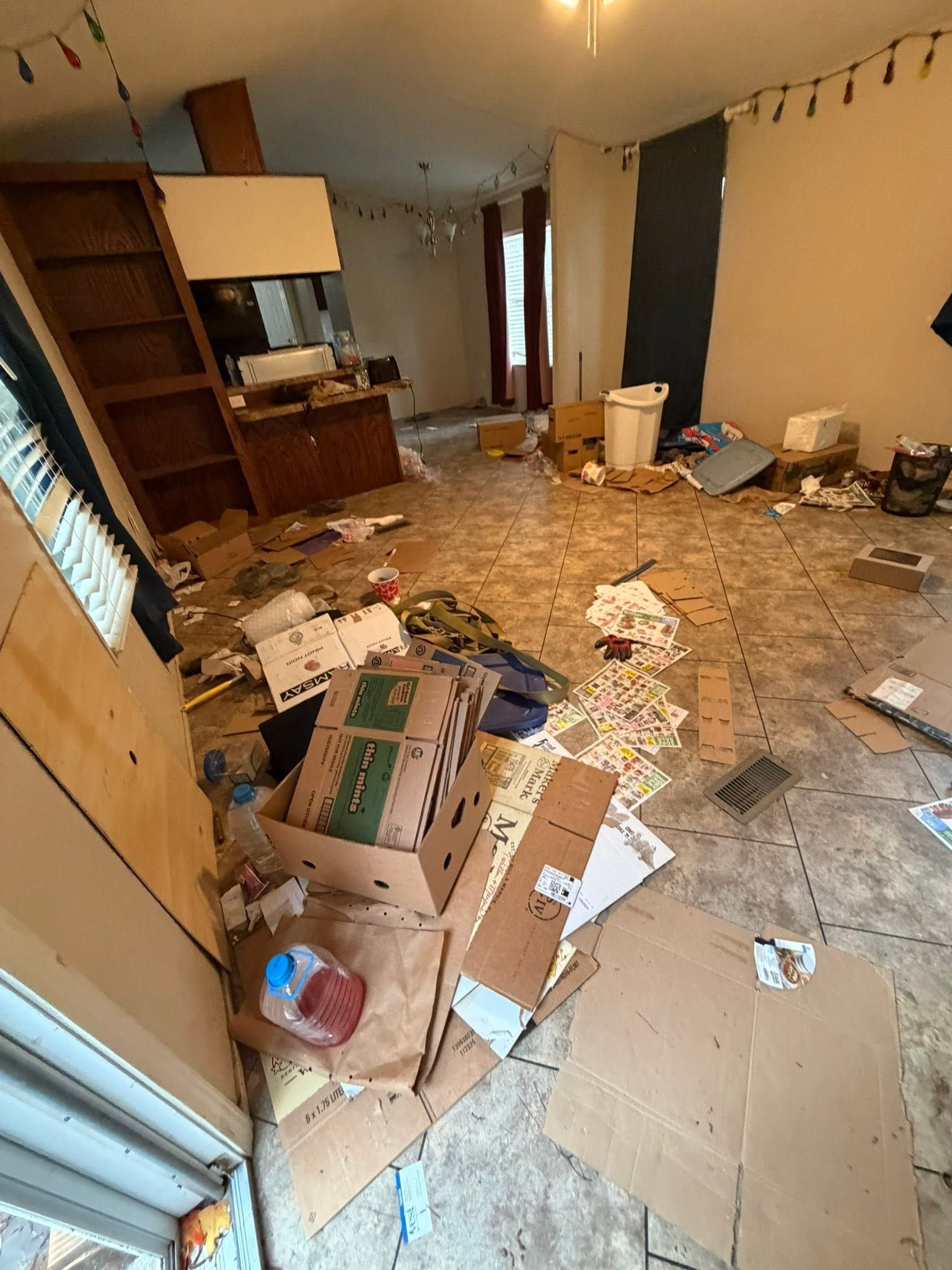 Messy apartment interior with scattered debris, broken boxes, and papers on the floor