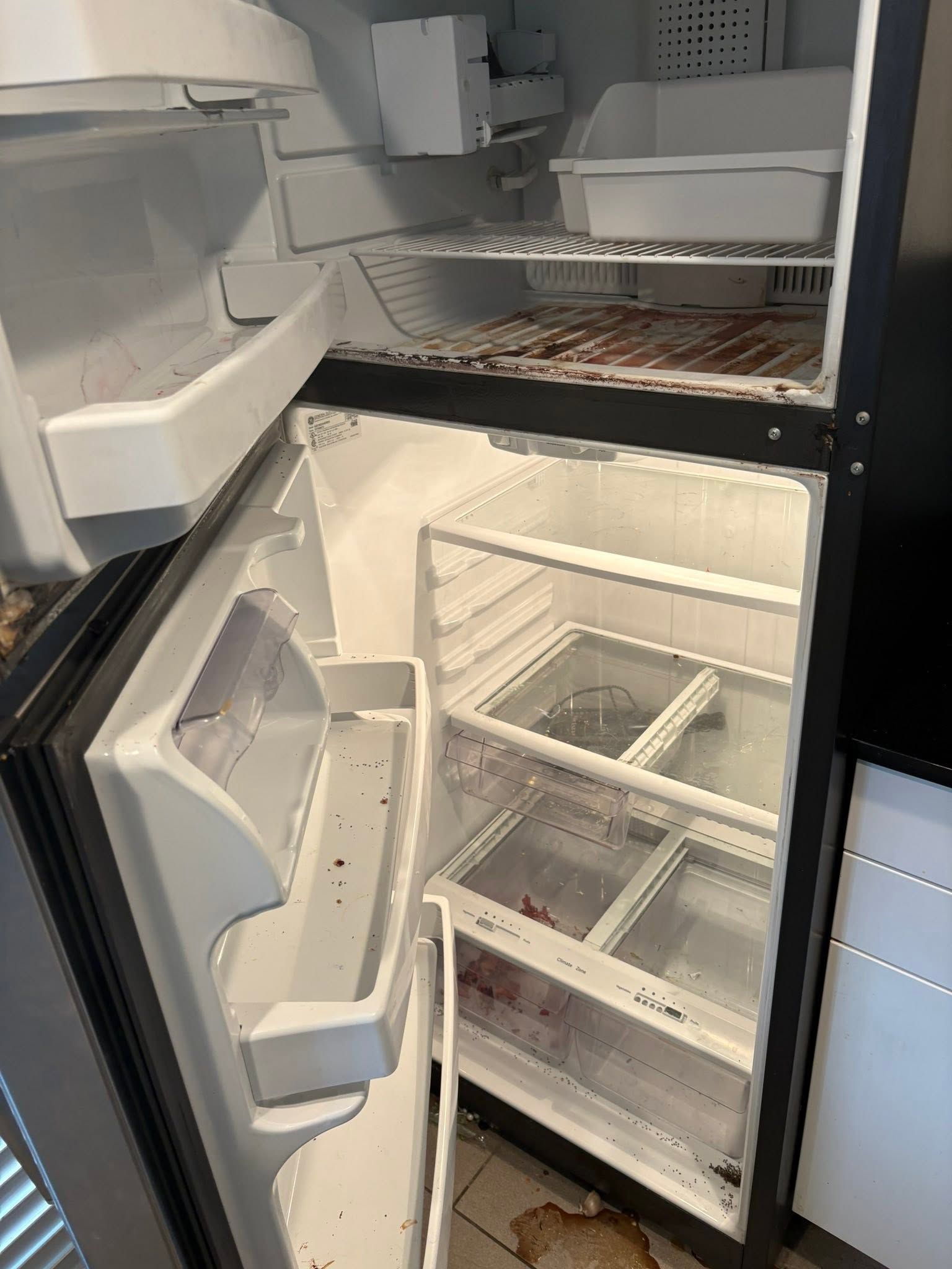 Open refrigerator with empty shelves and drawers, showing the freezer compartment inside.