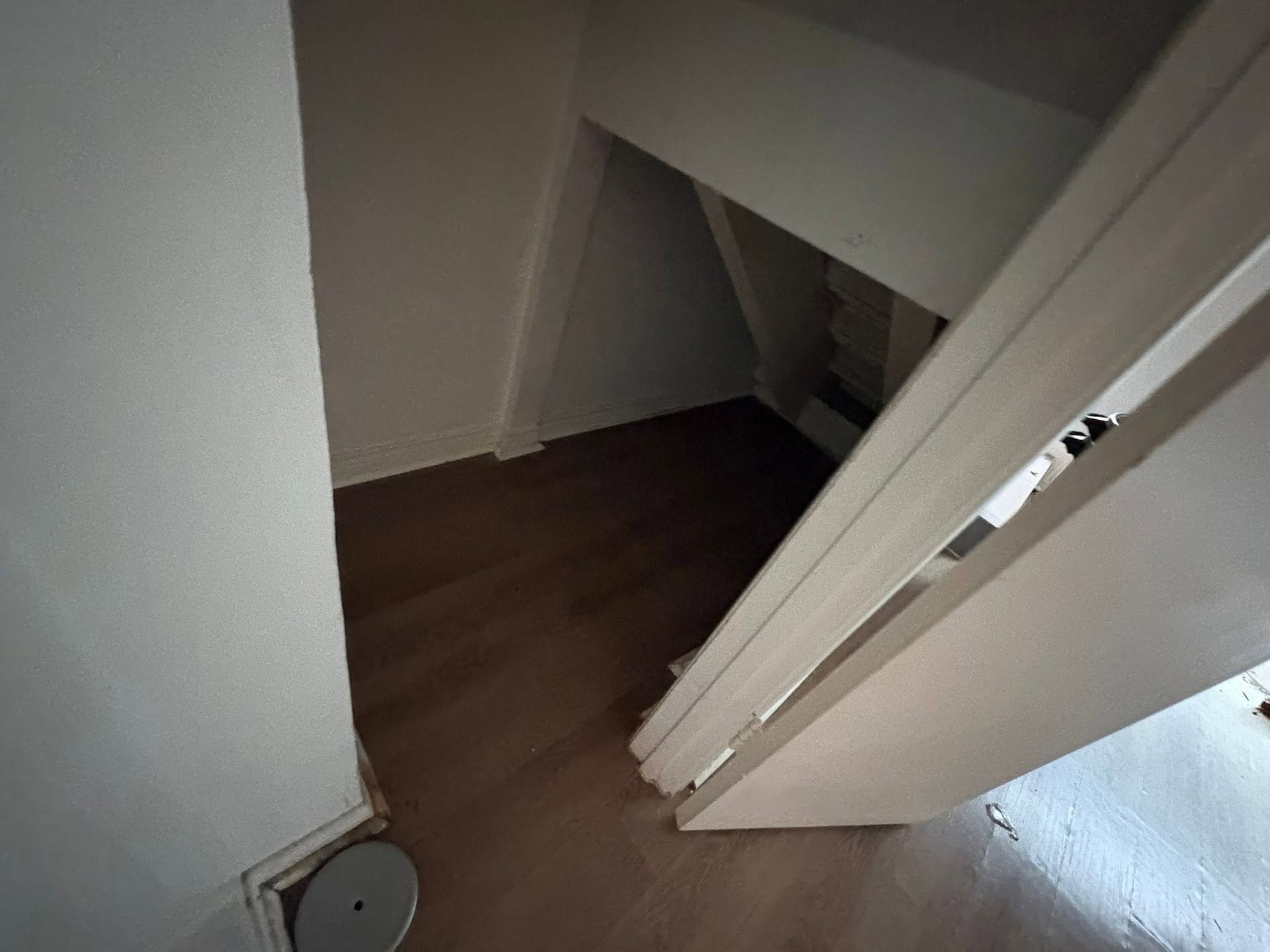 Open closet with white doors and dark wood floor, viewed from above.