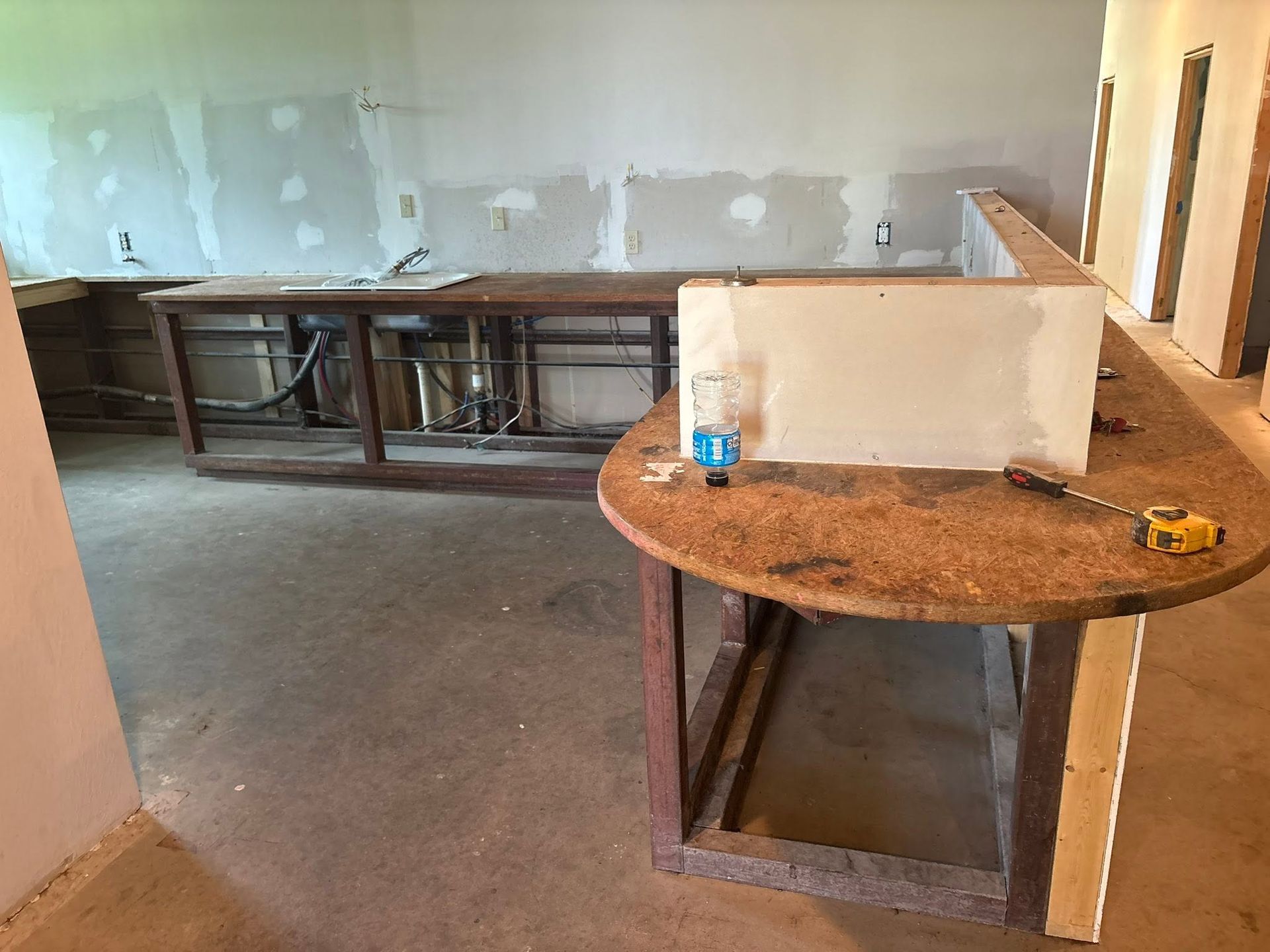 Renovation site with unfinished bar counter, concrete floor, and tools on a round work table