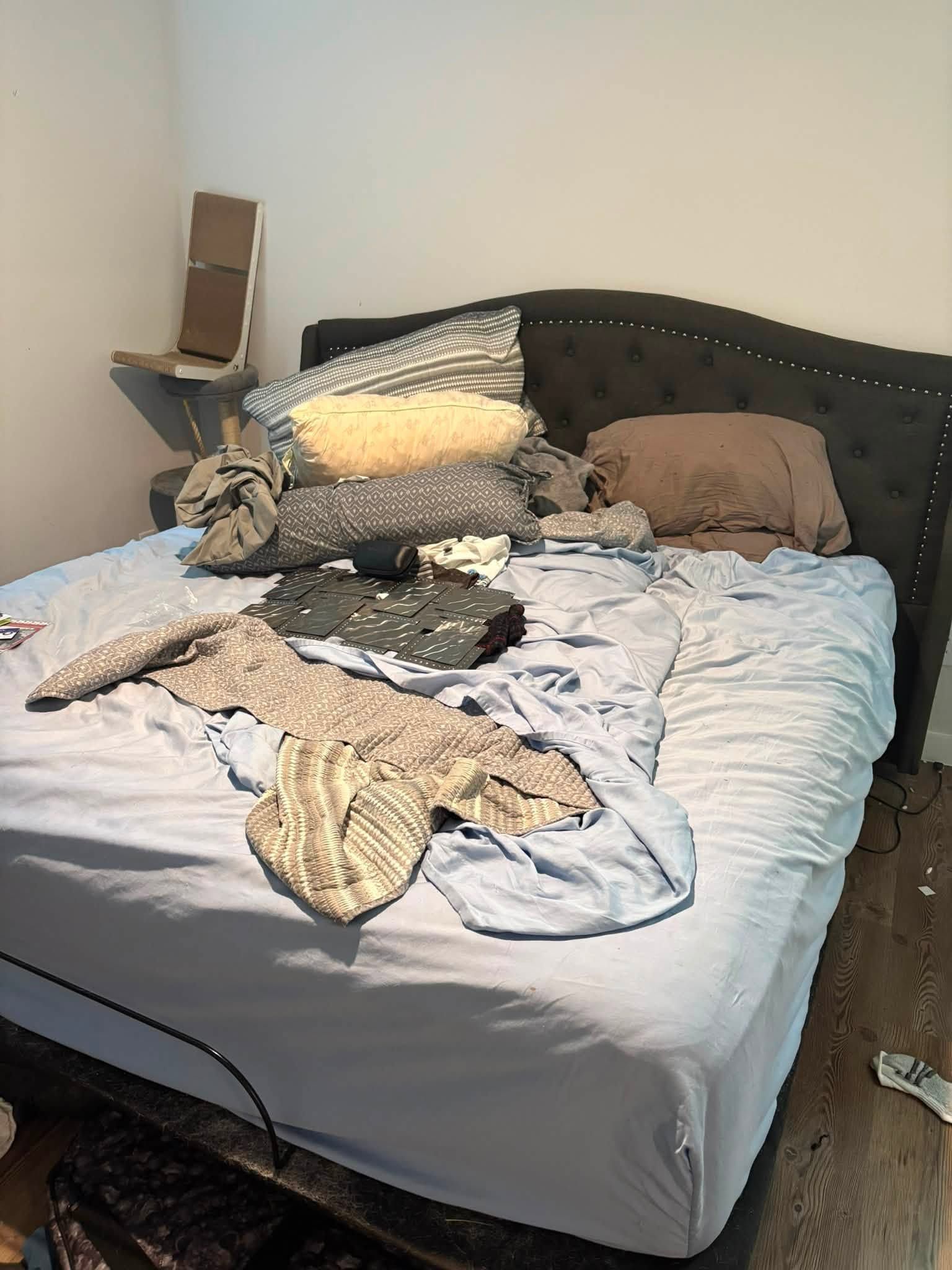 A messy bed with clothes and blankets piled on it in a bedroom.
