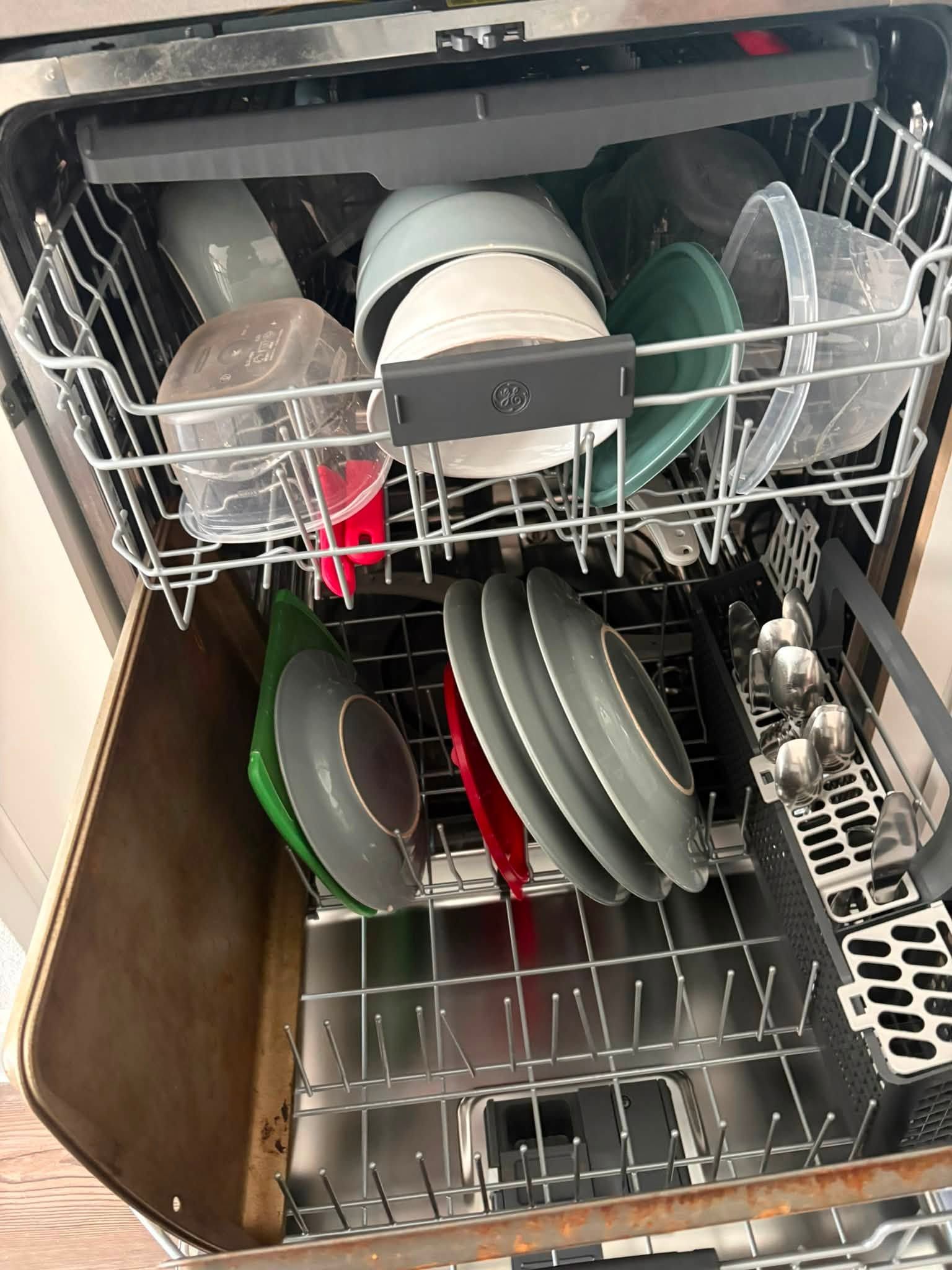 Open dishwasher with clean plates, bowls, and cups loaded in racks.