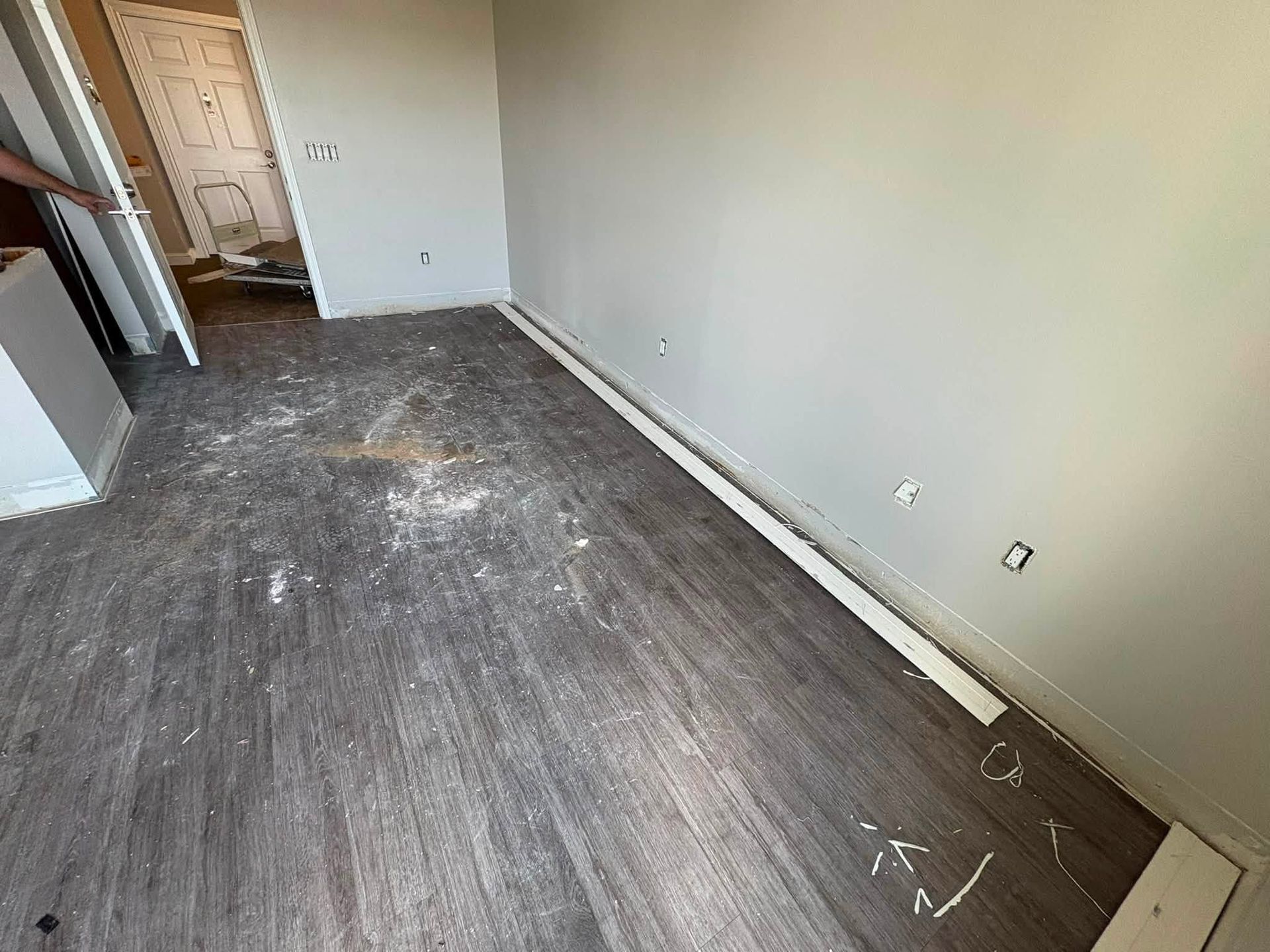 Empty room with dark wood floor, white walls, and an open doorway to a hallway.