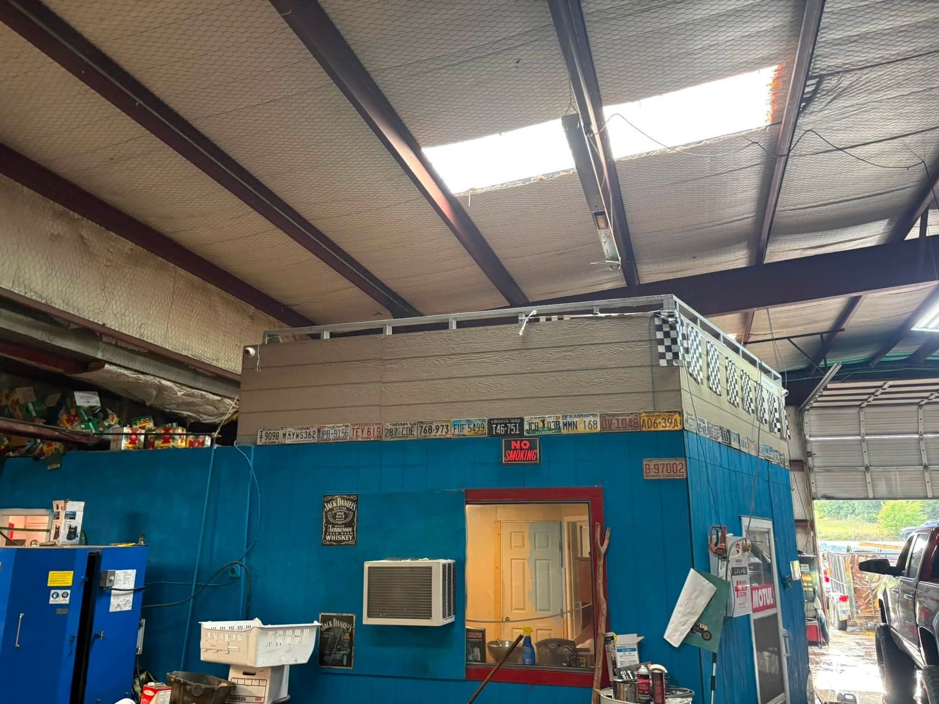 Blue service counter in a warehouse-like workshop with a corrugated metal roof and stacked items.