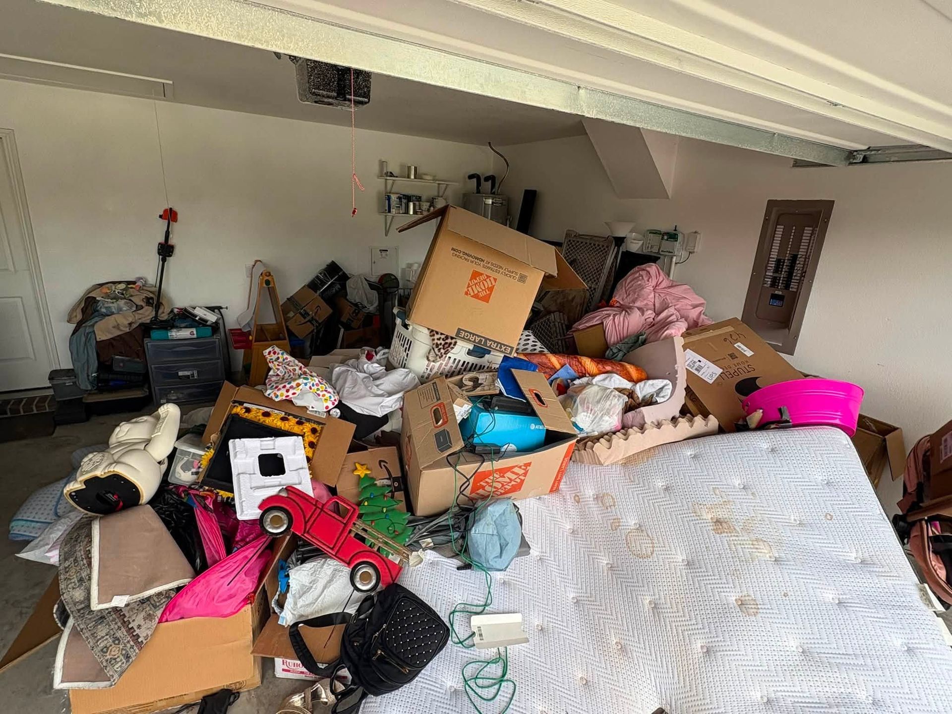 Cluttered attic filled with boxes, bags, and household items piled under a sloped ceiling
