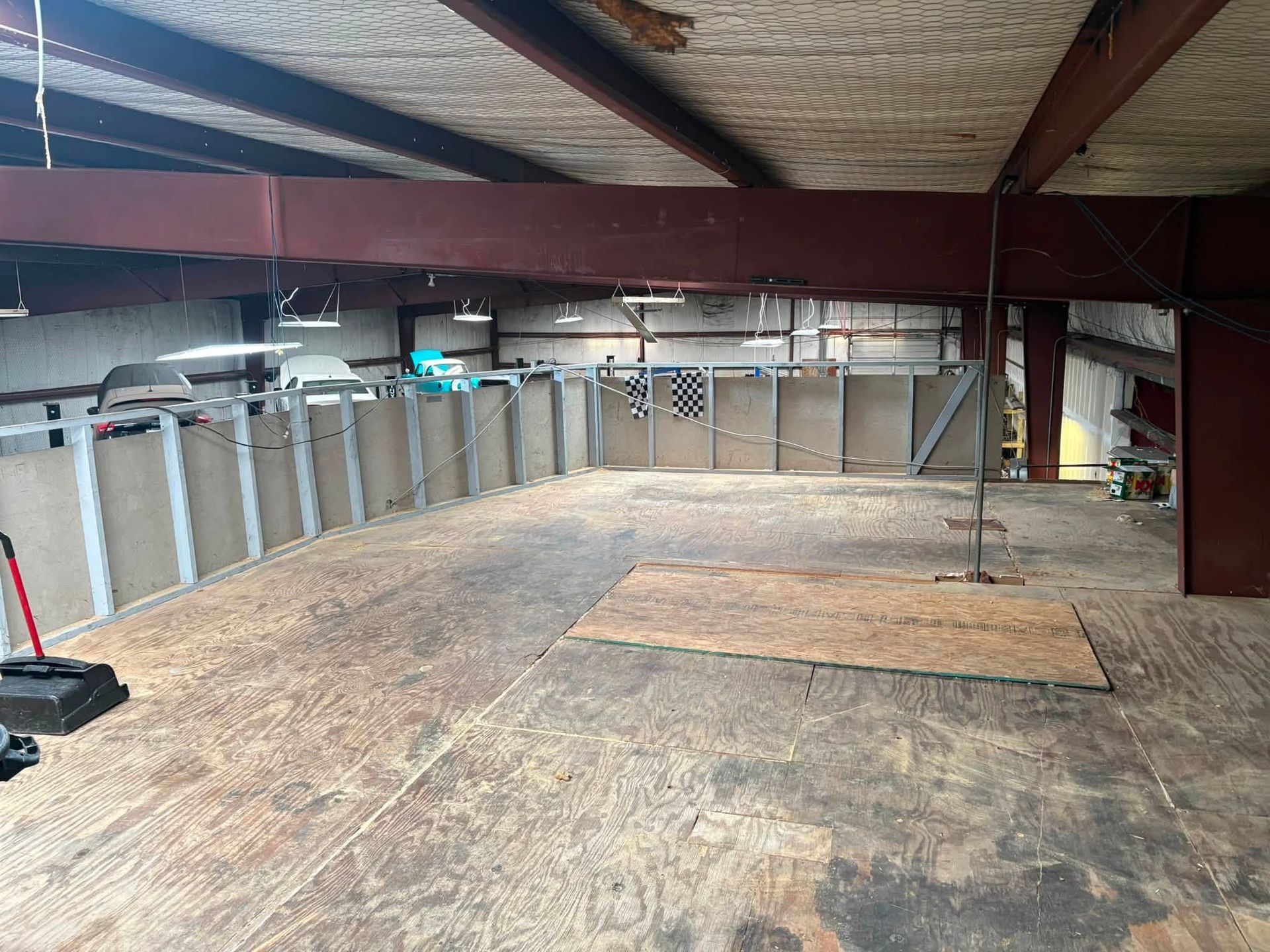 Empty loft or attic with plywood floor, exposed insulation, and metal support beams.