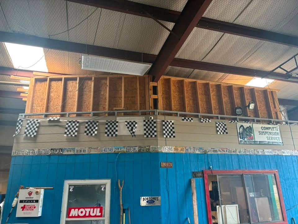 Blue storefront with MOTUL sign, checkered trim, and exposed wooden roof beams inside a warehouse-like space