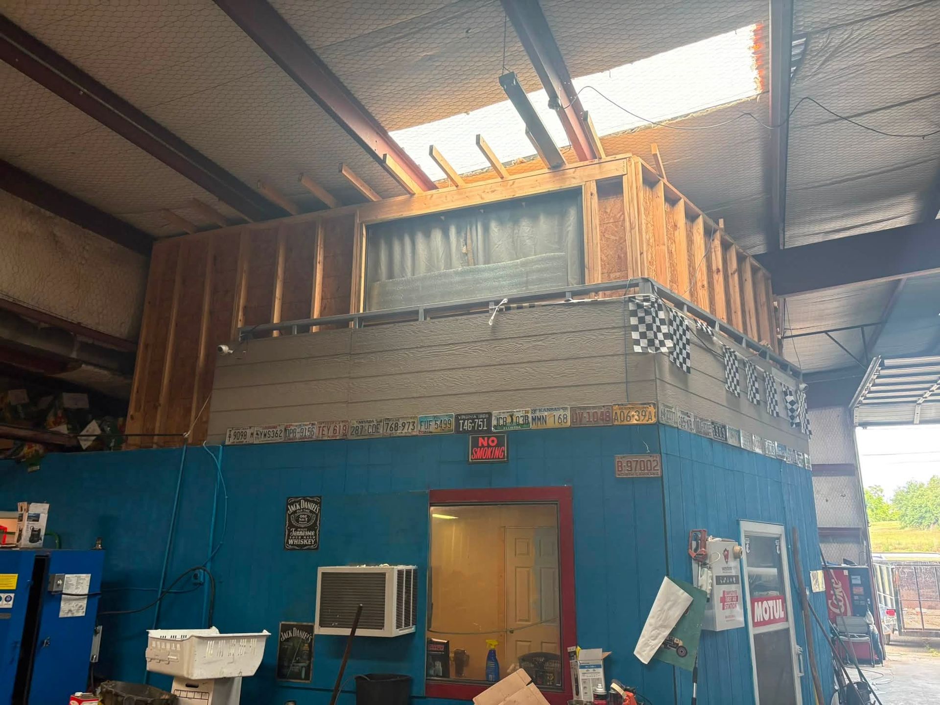 Blue industrial building with upper loft, open doorway, and stacked materials inside a warehouse.