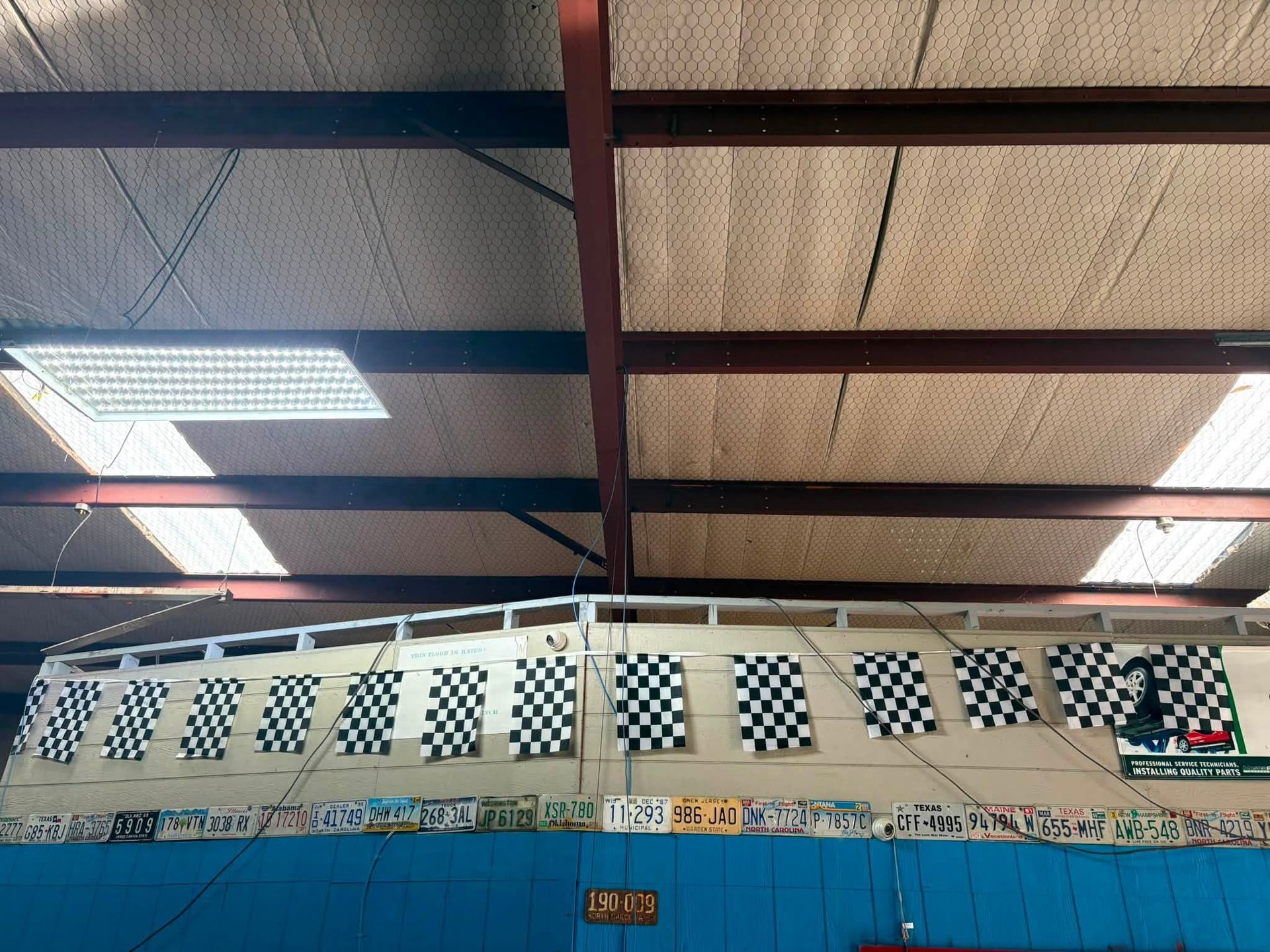 Indoor sports hall ceiling with blue and red beams, bright lights, and checkered wall vents
