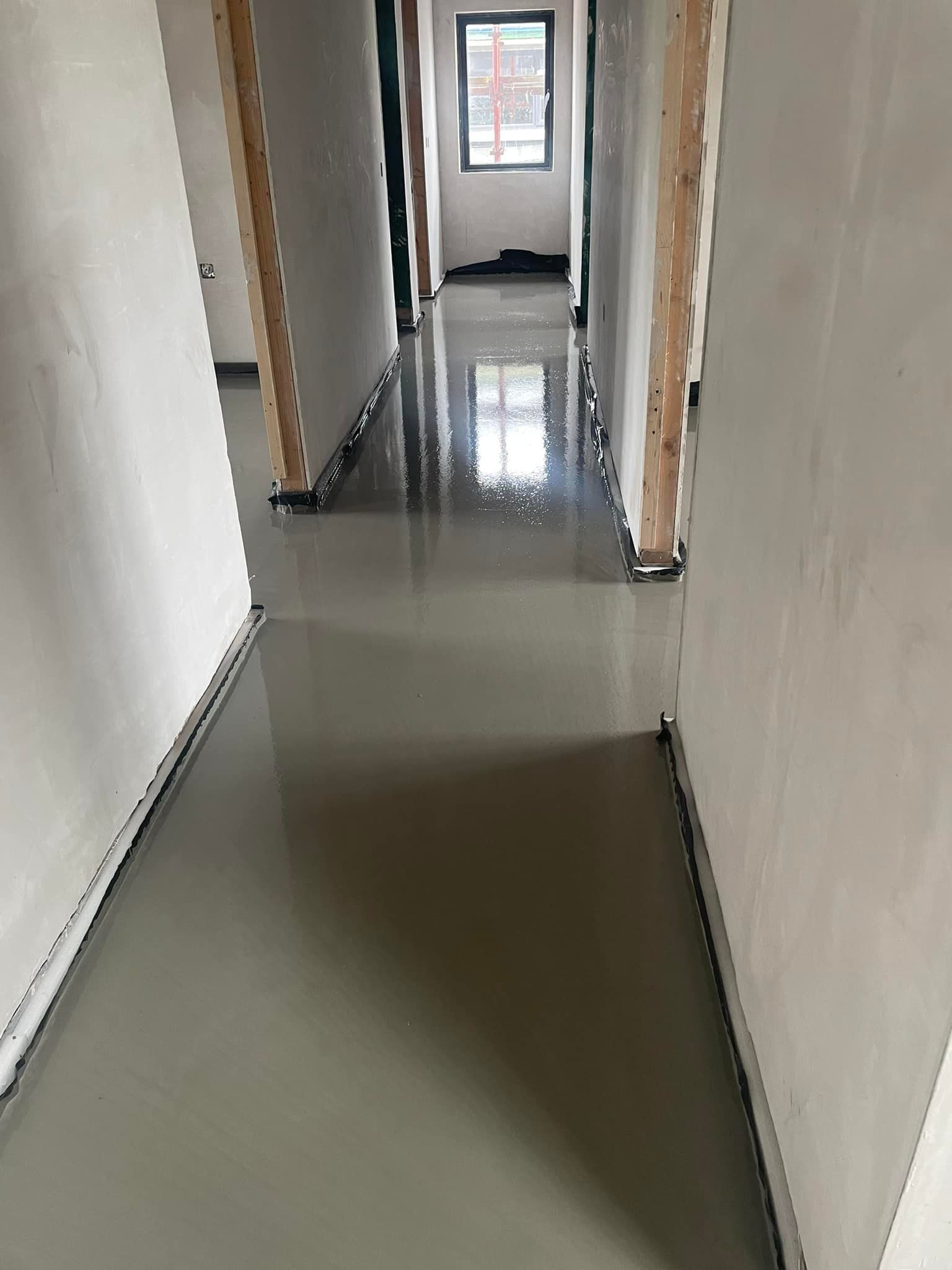 A long hallway with a concrete floor in a building under construction.