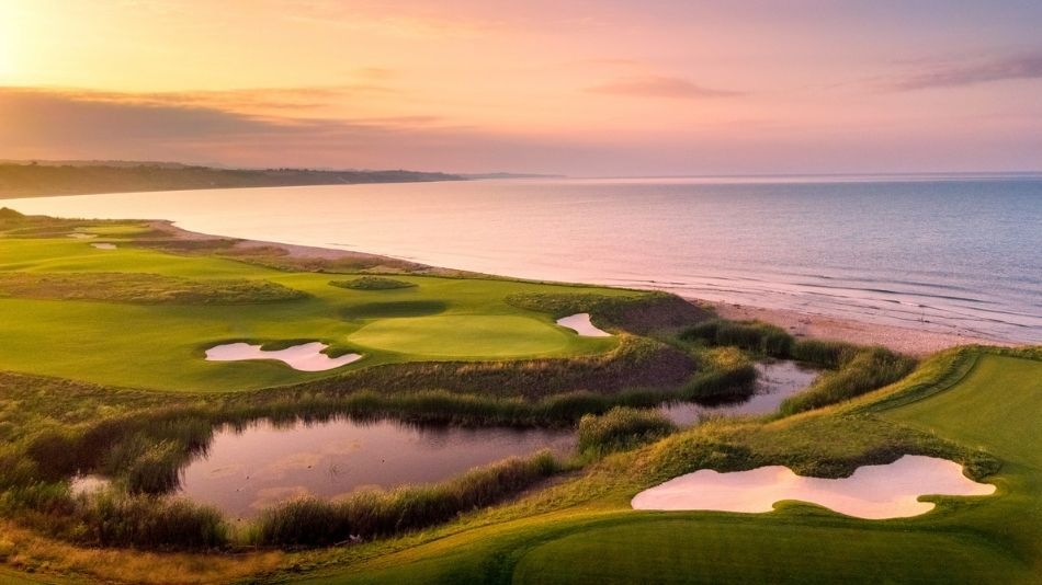 Championship Golf. Sunset over a coastal golf course with sand traps and reflective water along the shoreline