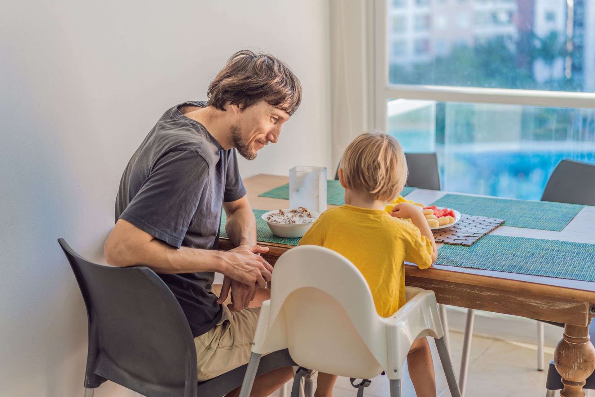 Adult and child painting at a dining table near a bright window