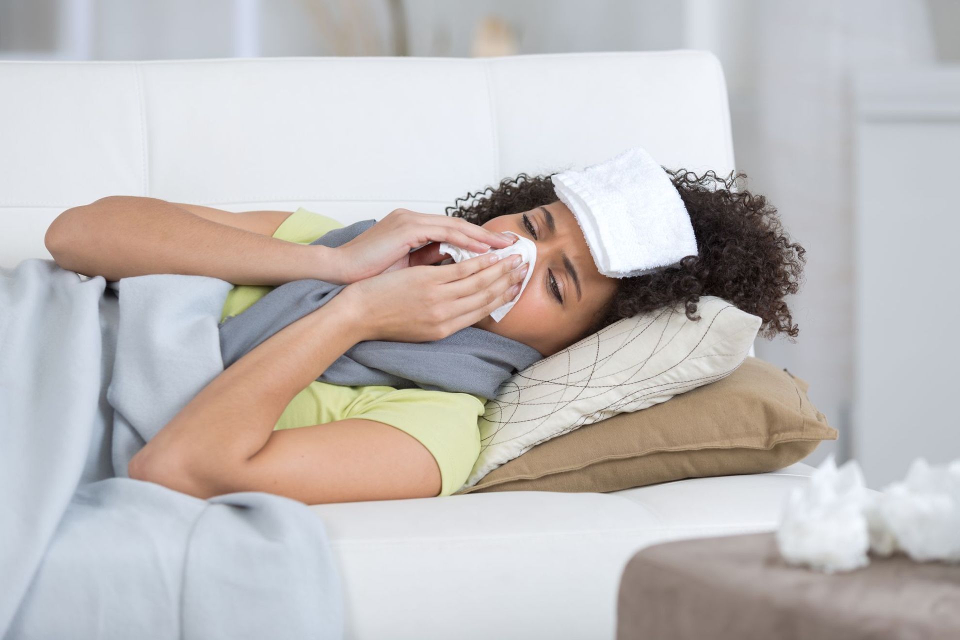 sick woman on sofa blowing nose