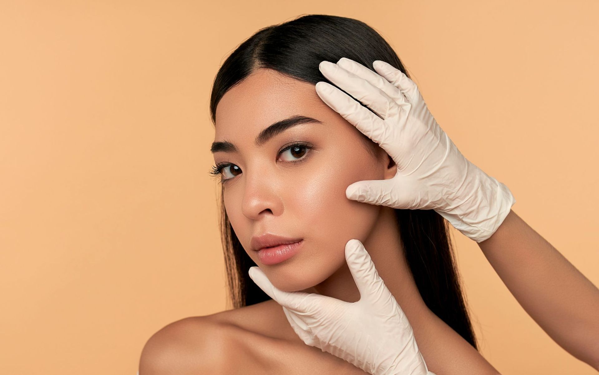 beautiful woman with gloved doctor's hands on face