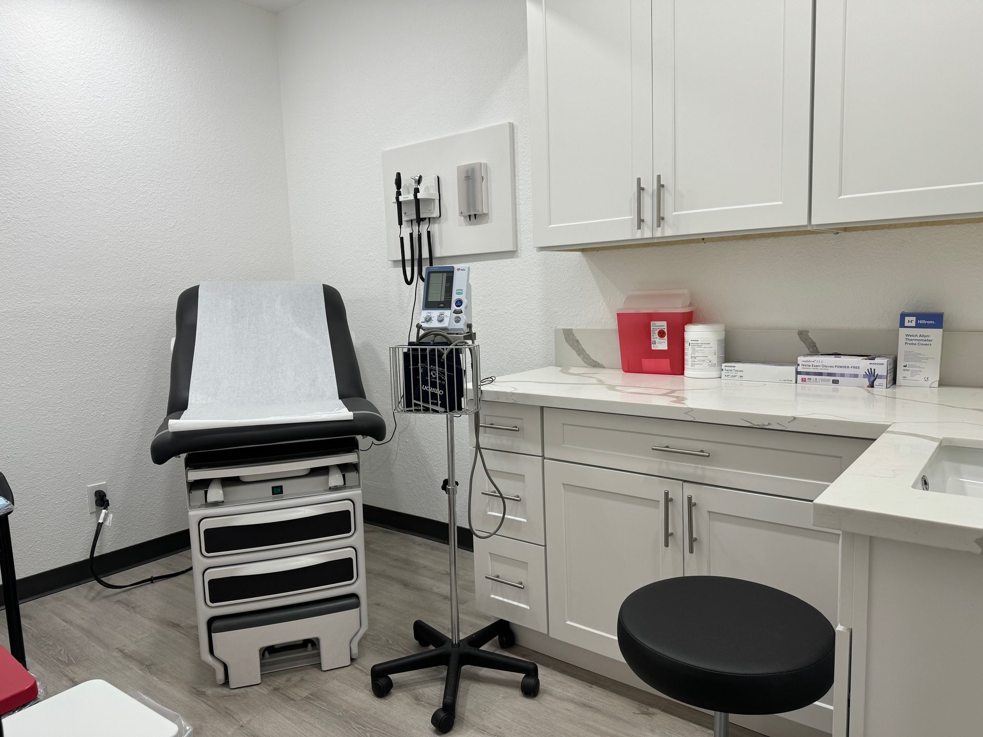 inside the doctors office is an examination chair on the left and on the right is the sphygmomanometer, counter and sink