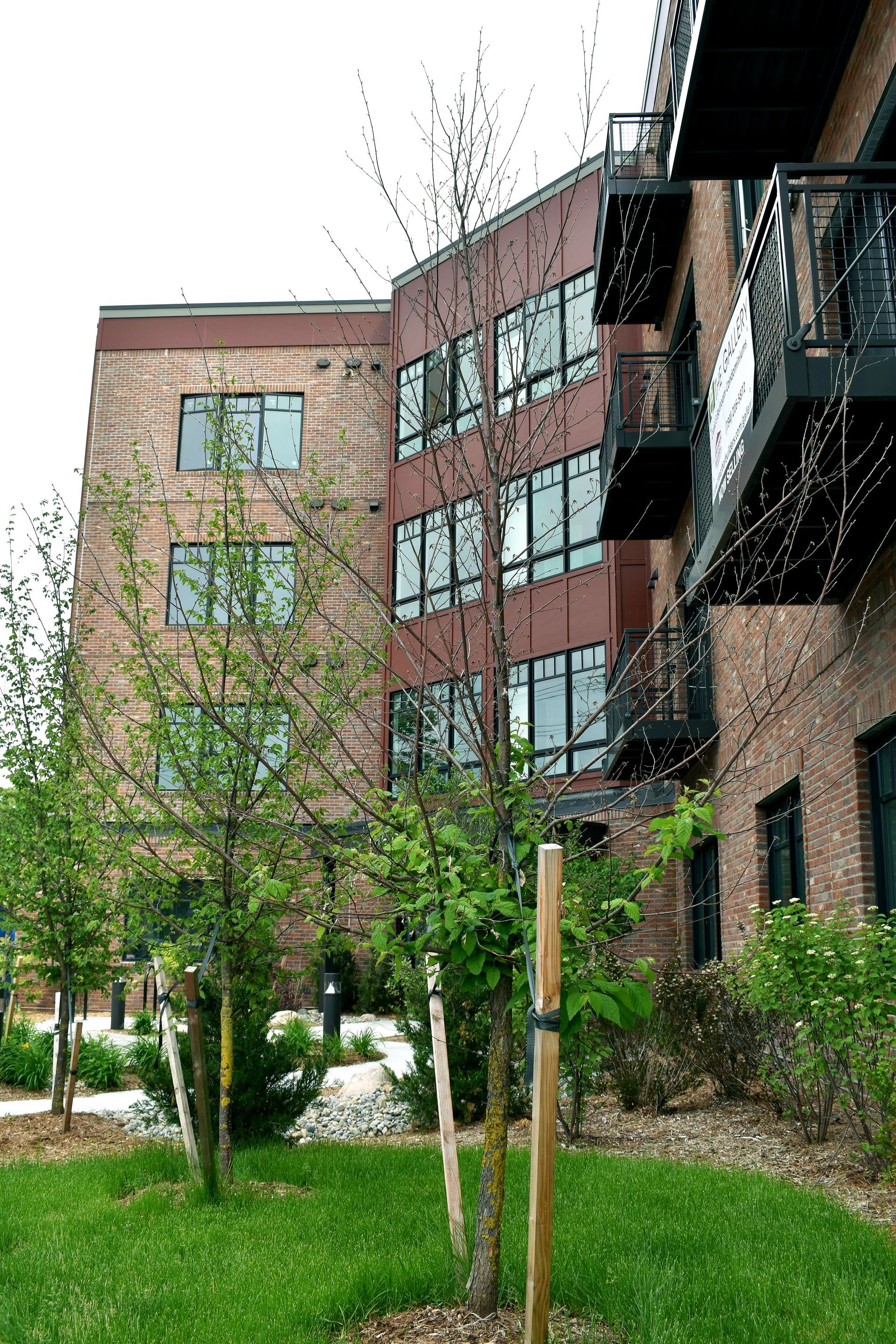A large brick building with a lot of windows is surrounded by trees and grass.