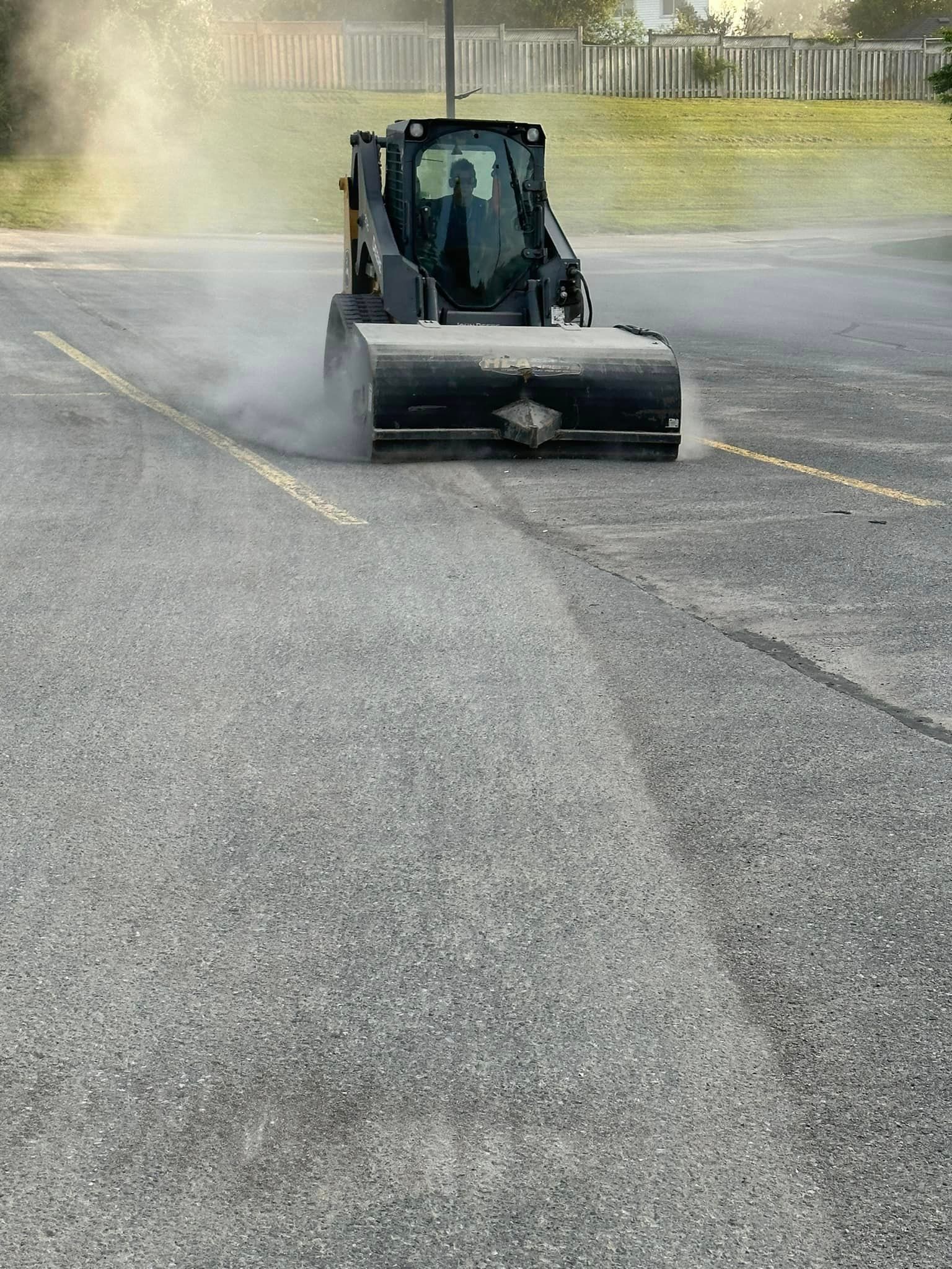 A bulldozer is cleaning the asphalt in a parking lot.