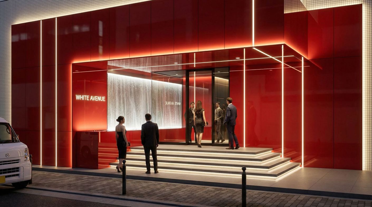 People walk up the steps toward the brightly lit entrance of a modern, red-paneled building at night.