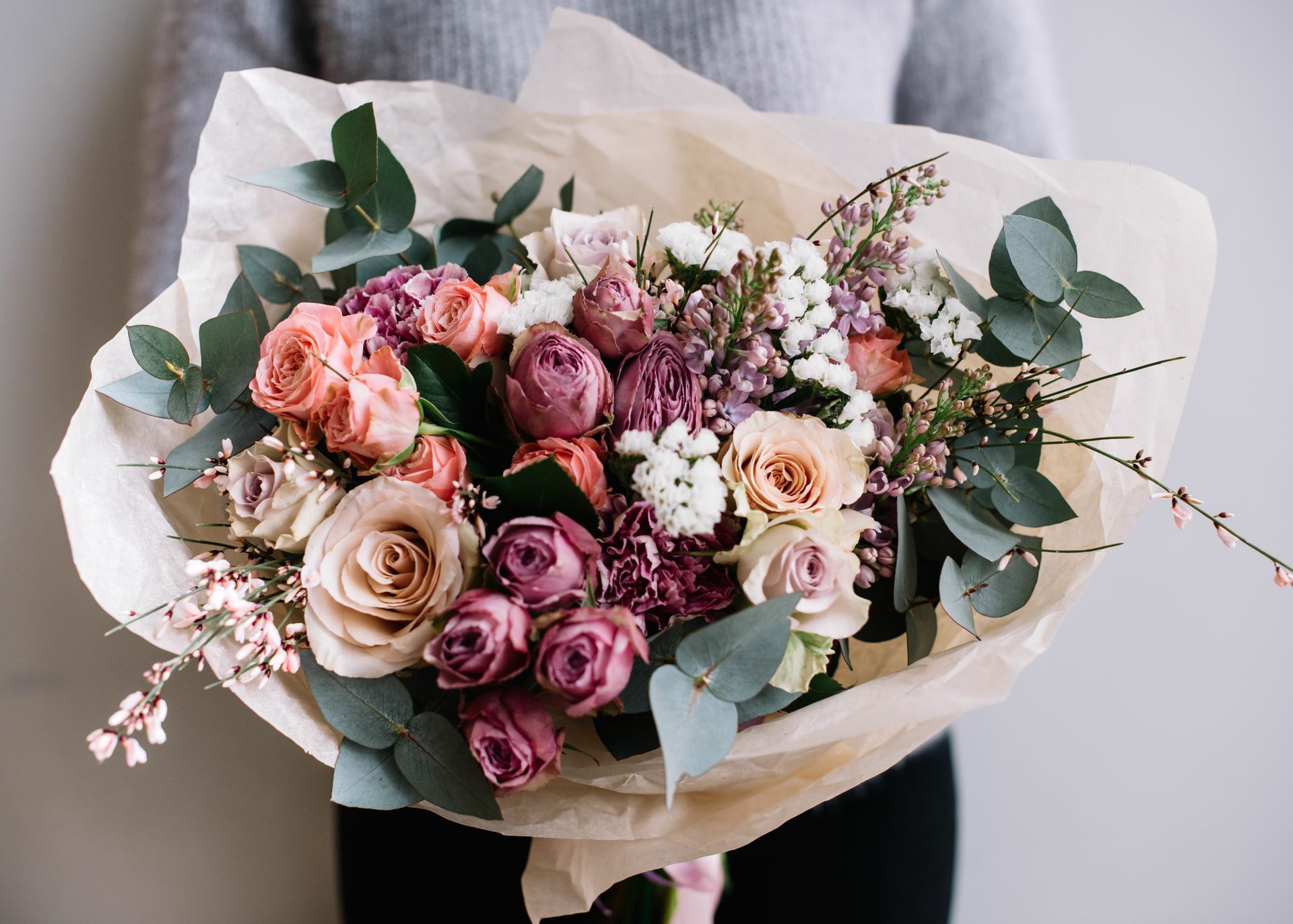 Bouquet de roses roses et crème avec eucalyptus et papier d'emballage blanc