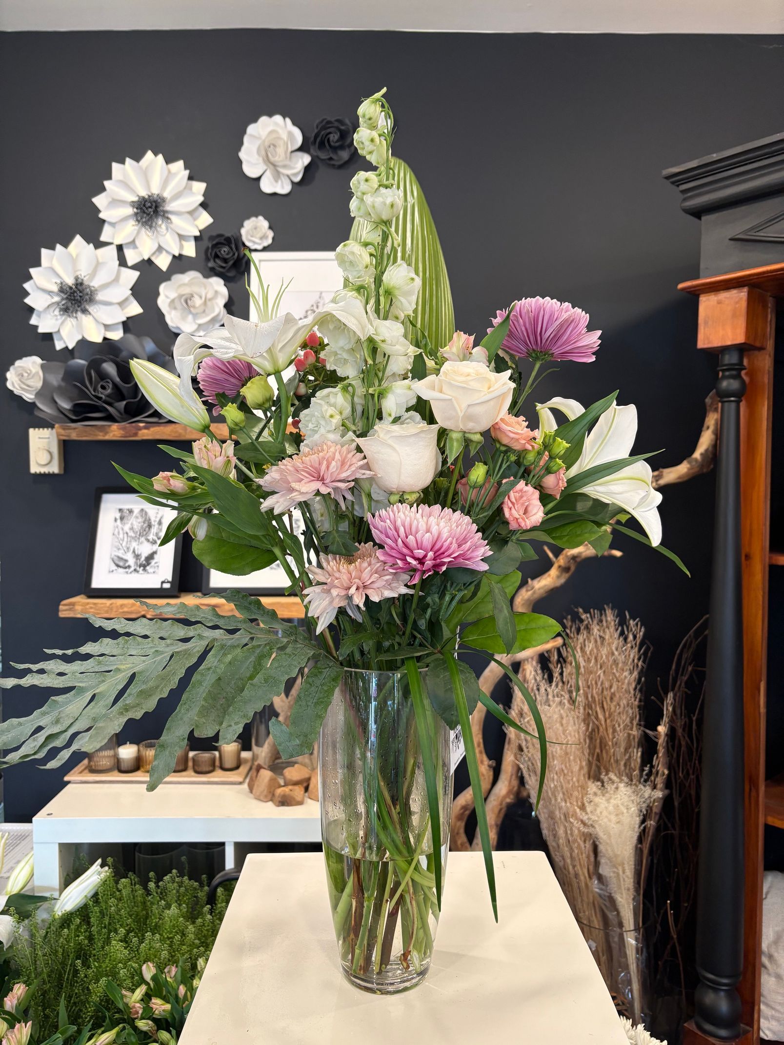 Grand arrangement floral mixte dans un vase en verre, composé de fleurs roses, blanches et vertes, pour l'intérieur.