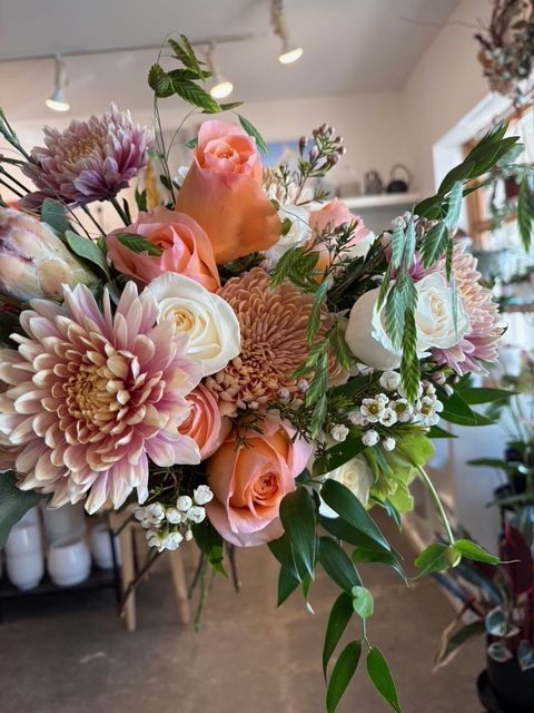Bouquet composé de roses roses, de dahlias et de verdure dans une boutique de fleurs