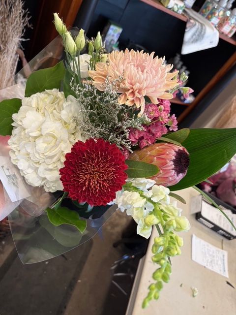 Bouquet de fleurs blanches, roses et rouges avec des feuilles vertes sur une table dans un cadre intérieur