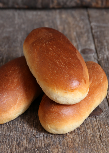 Drie goudbruine broodjes opgestapeld op een verweerd houten oppervlak.