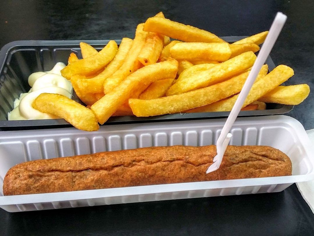 Friet/patat met mayonaise en een frikandelworst, geserveerd in bakjes.