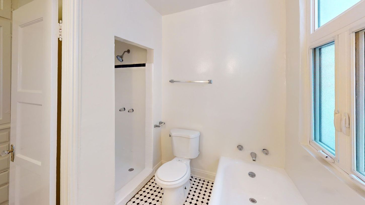 White bathroom with shower, toilet, and bathtub. Black and white tile floor.
