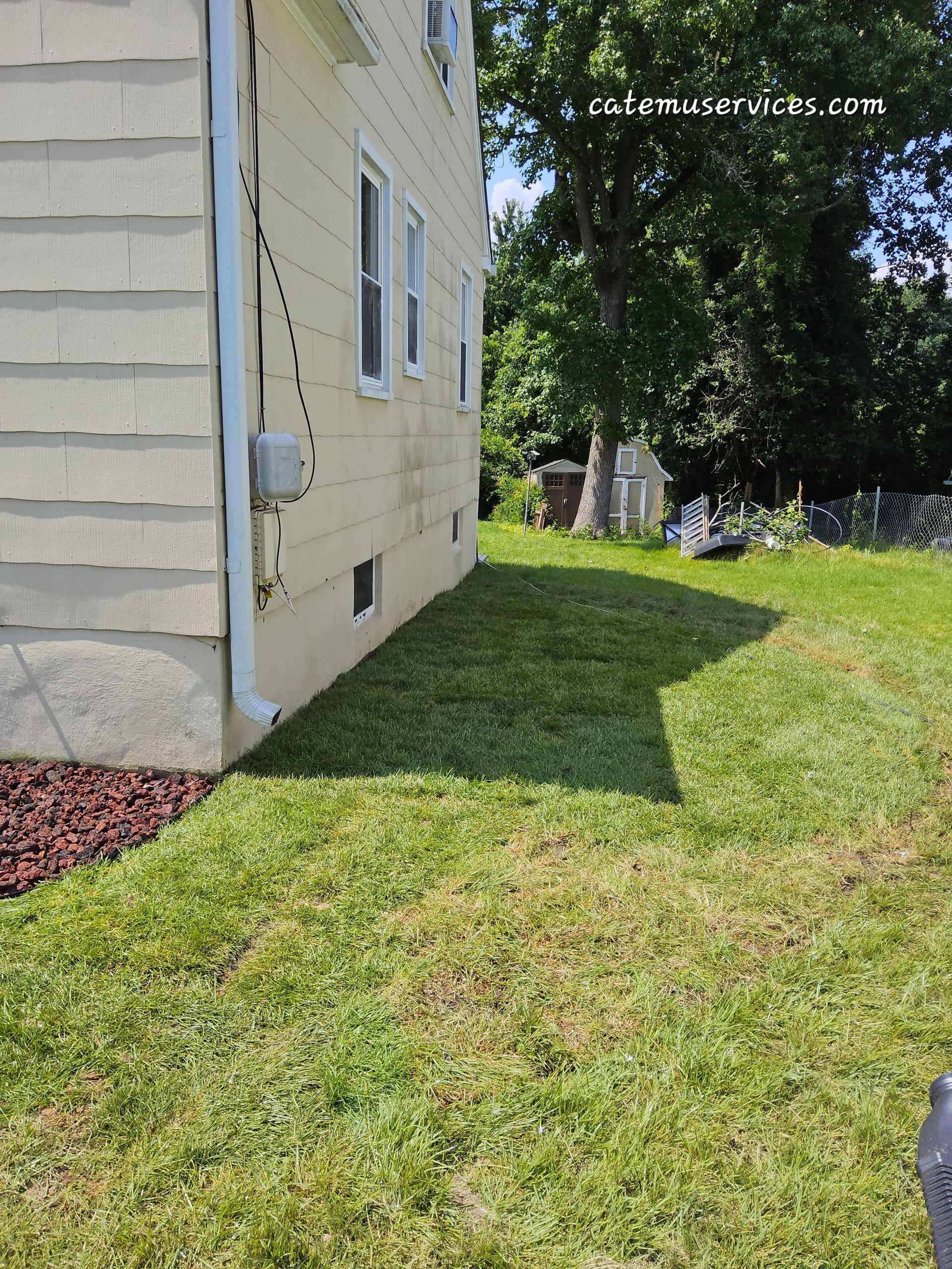 Side view of a yellow house with a freshly mowed green lawn.