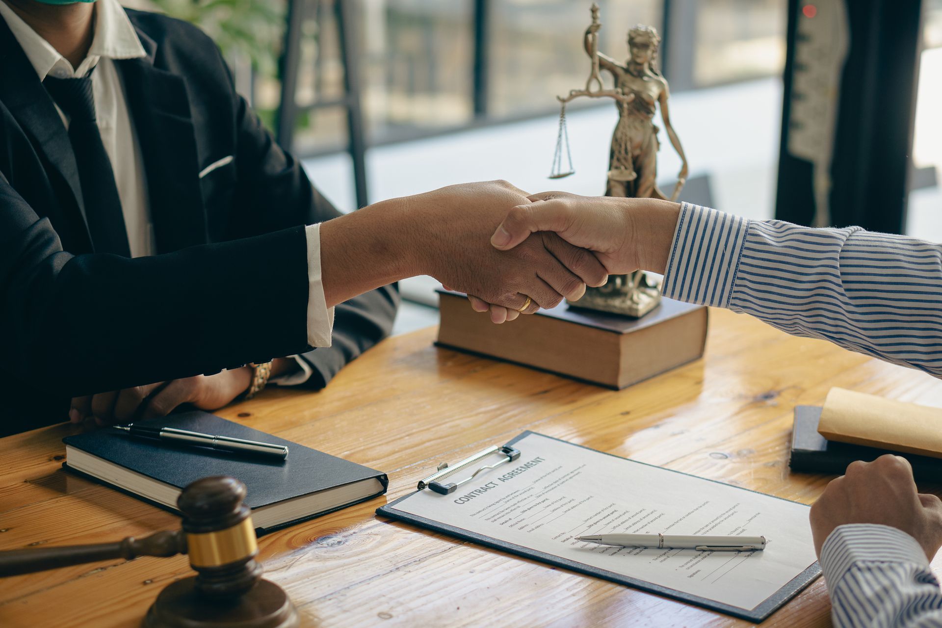 A lawyer is shaking hands with a client at a table.