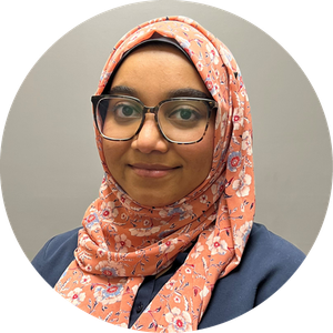 Portrait of a smiling person wearing glasses and a floral peach hijab against a gray background