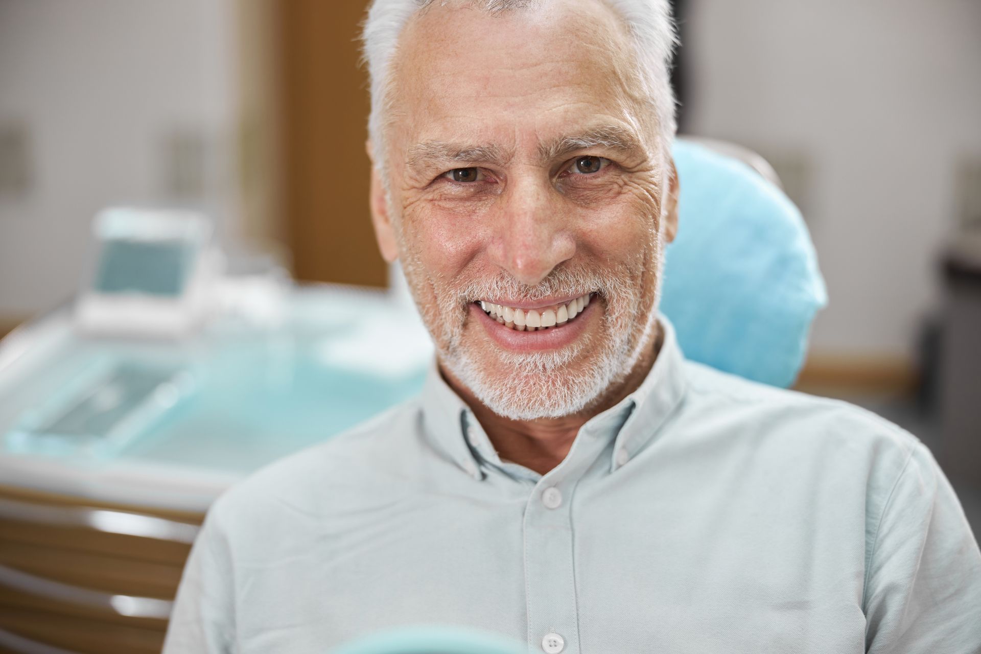 Man with gray hair smiling in a dental chair.