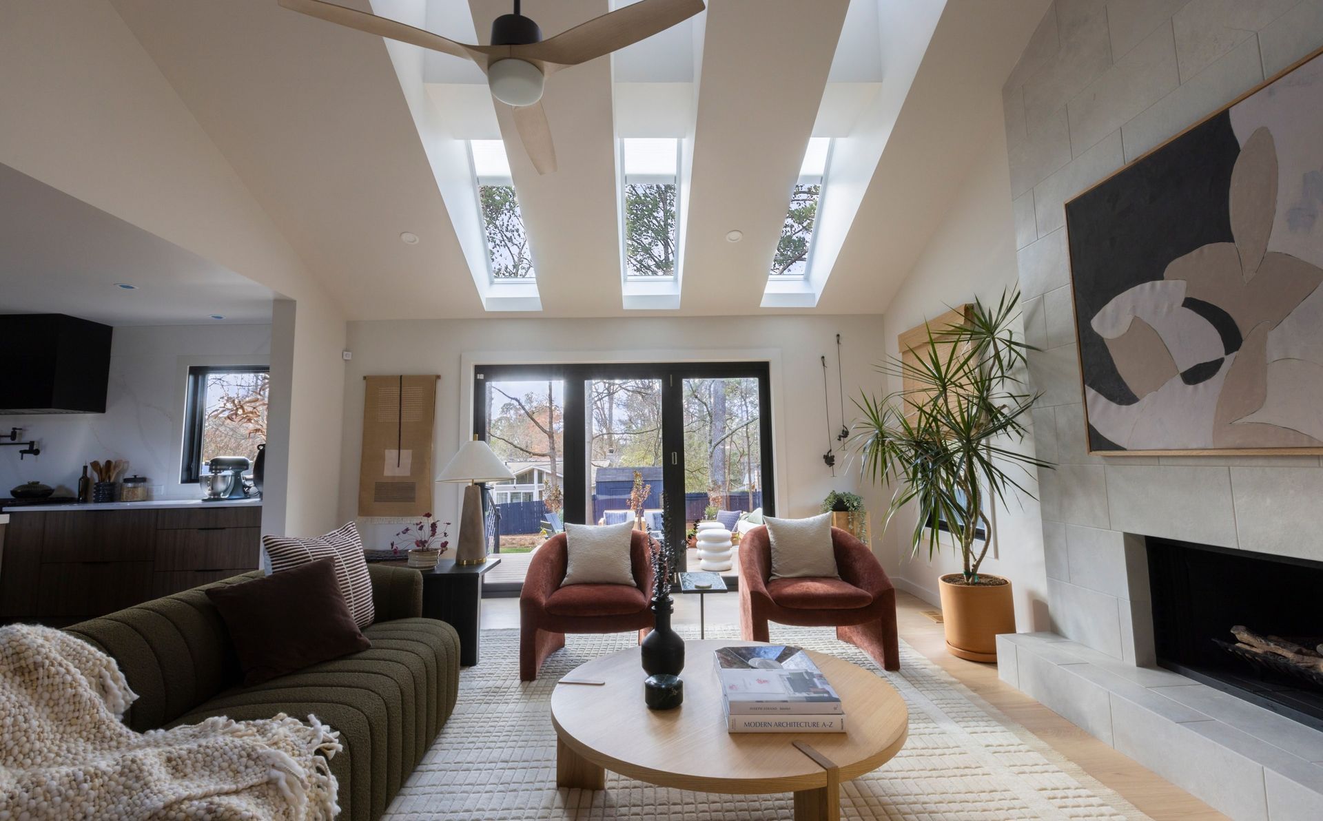 Living room with high ceilings, skylights, and a fireplace; furnished with modern seating.