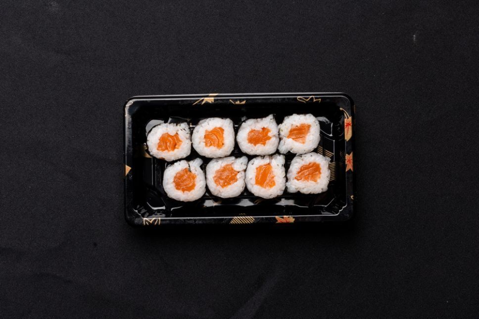 A tray of sushi rolls on a black surface.