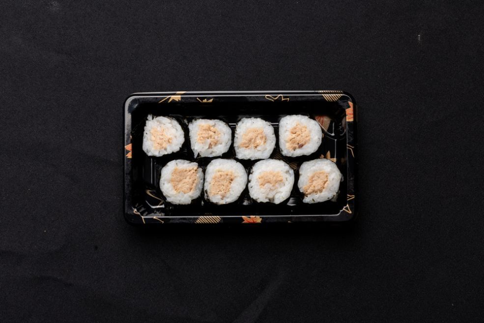 A tray of sushi rolls on a black surface.