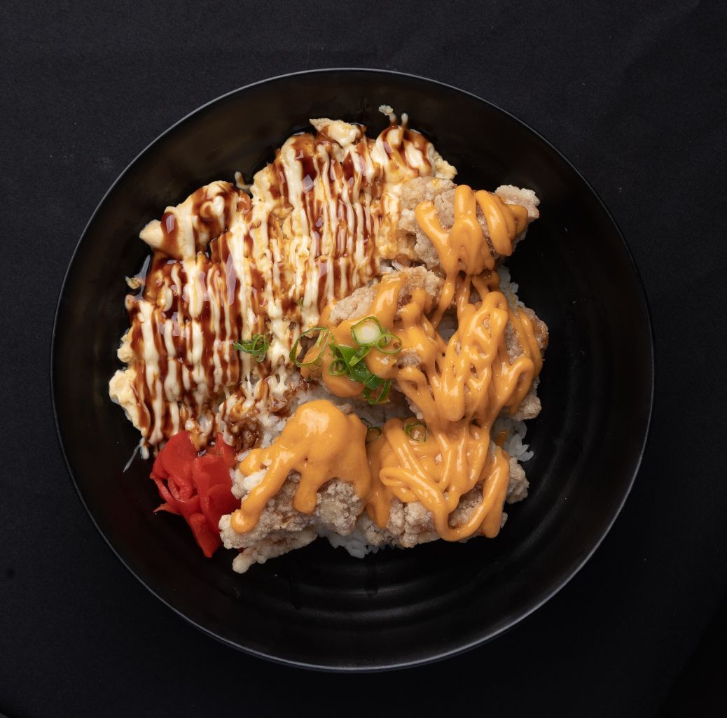 A black bowl filled with food and sauce on a table.