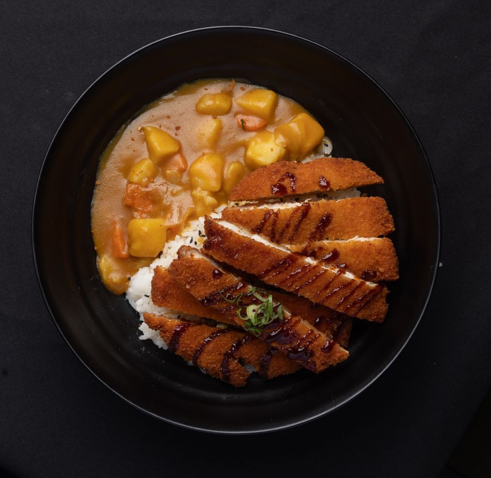 A bowl of food with meat and rice on a table