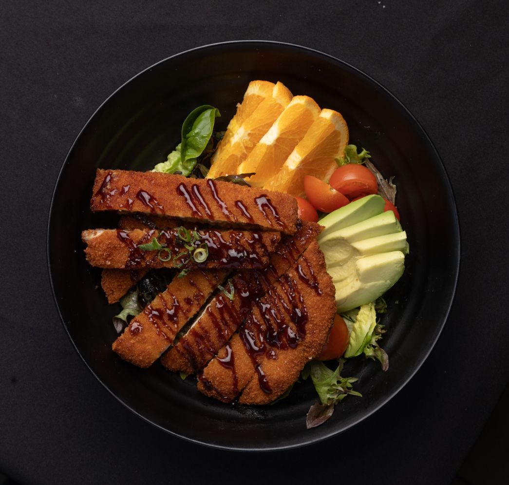 A black bowl filled with meat and vegetables on a table